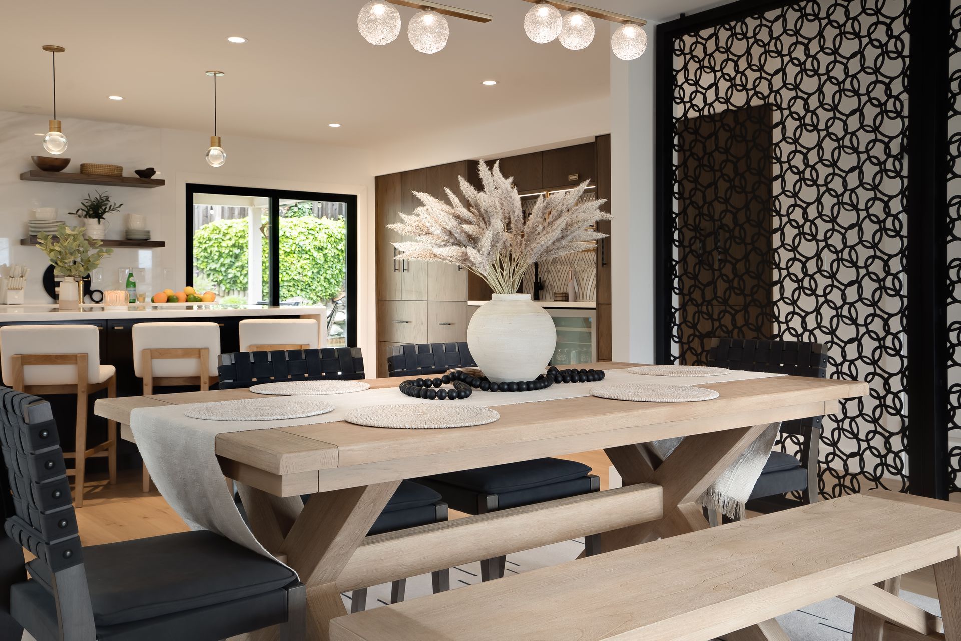 A dining room with a wooden table and chairs, a decorative screen, and a bar in the background.