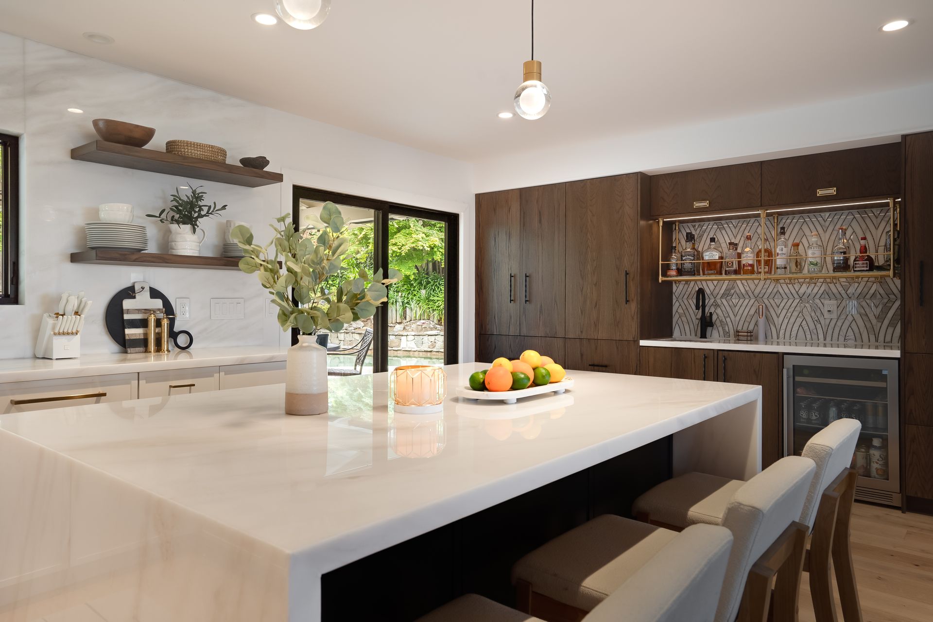 Modern kitchen with marble island, wood cabinets, and bar area.