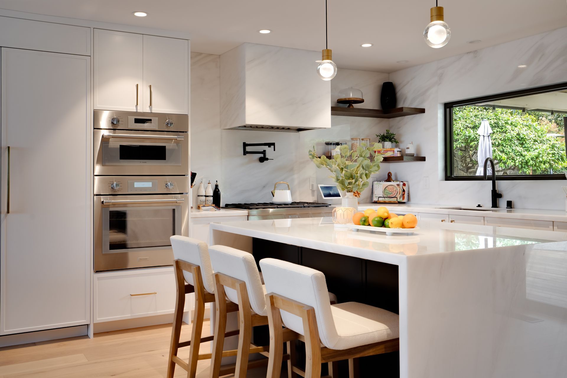 Modern kitchen with white cabinets, island, stainless steel appliances, and seating.
