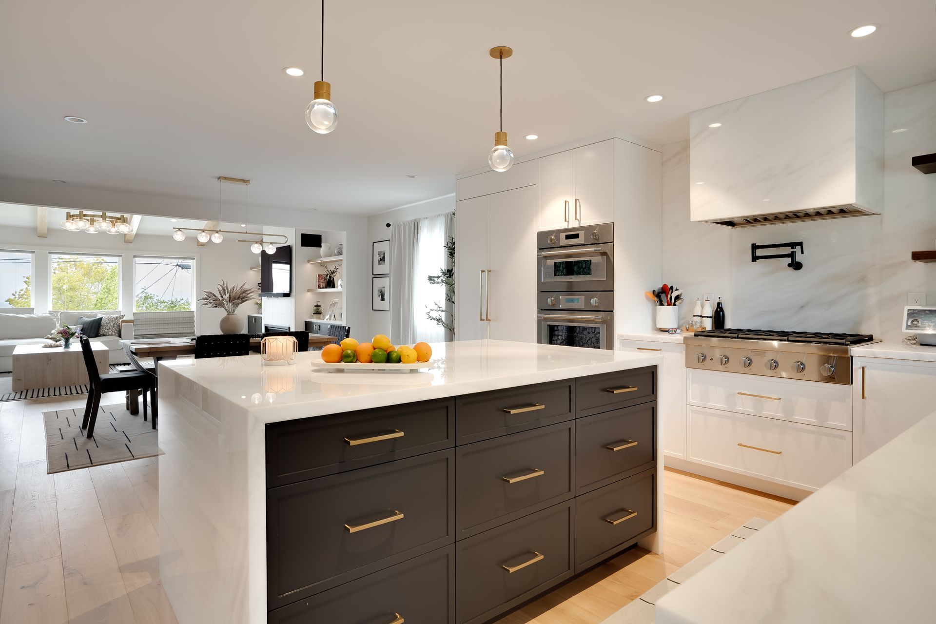 Modern kitchen with a dark island, white countertops, and stainless steel appliances.