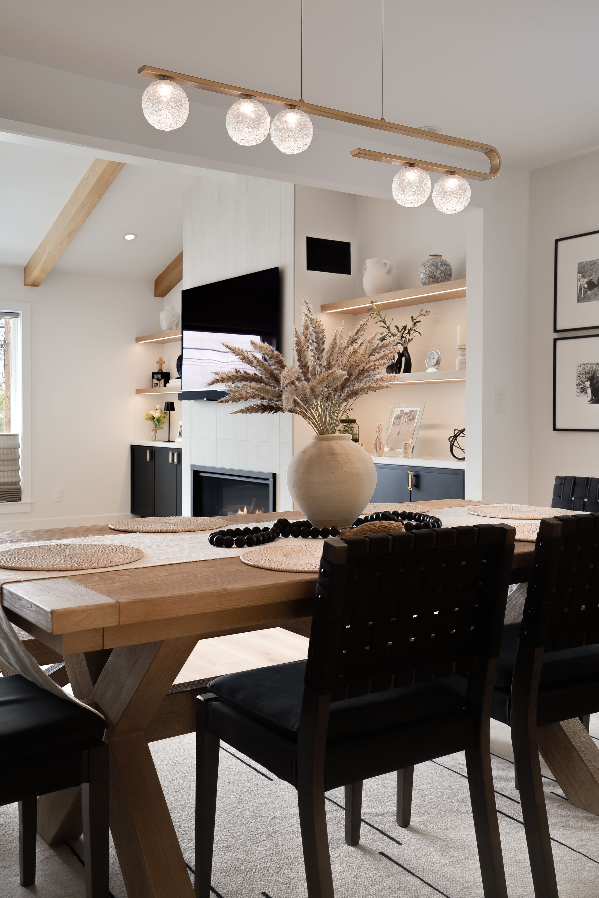 Dining room with a wooden table, black chairs, and a decorative light fixture.