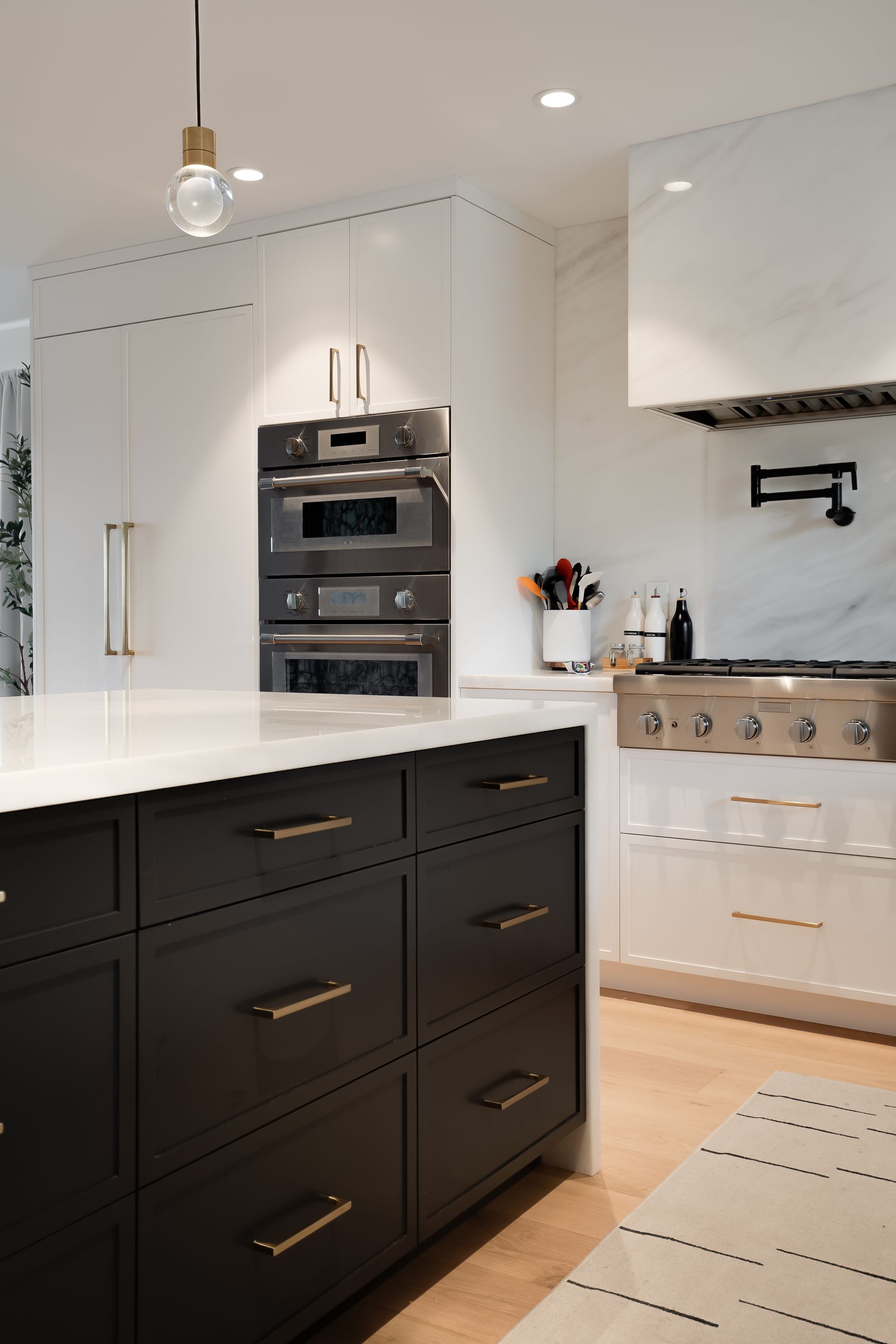 Modern kitchen with black island, white counters, and built-in oven.