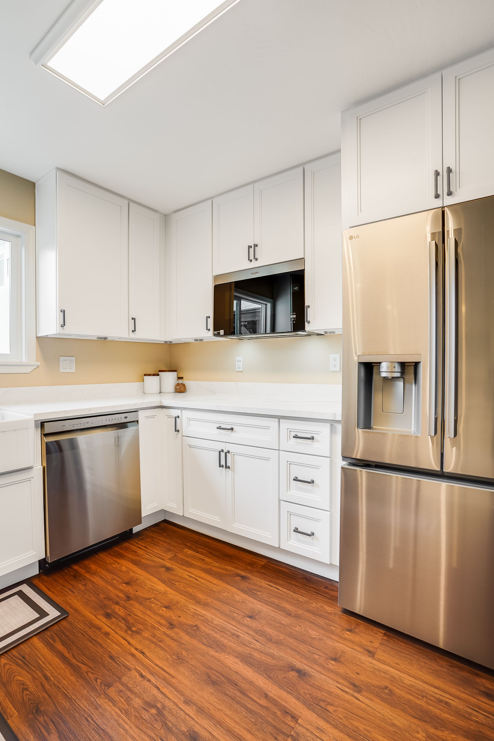 Modern white kitchen with stainless steel appliances and hardwood floors