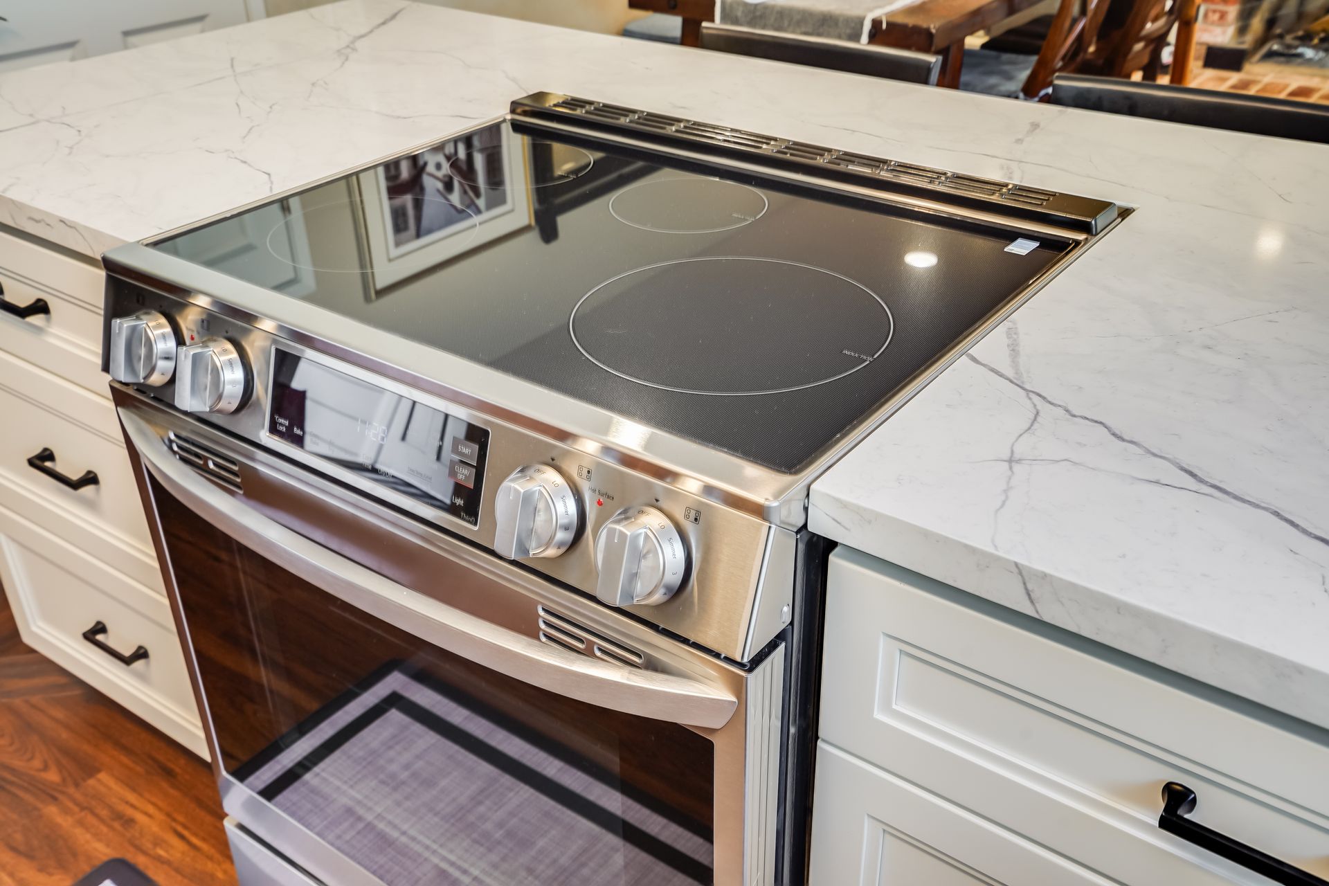 Built-in stainless steel induction cooktop and oven in a white marble kitchen countertop
