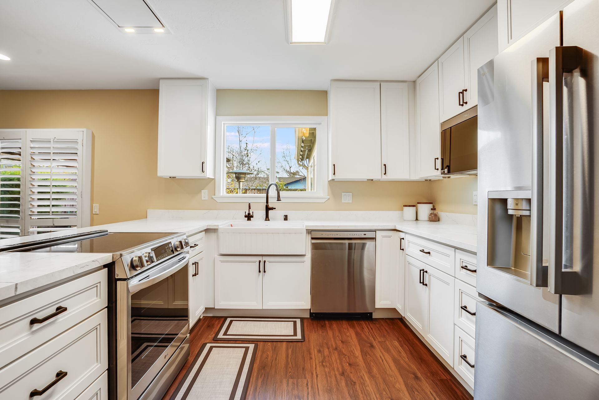 Bright modern kitchen with white cabinets, stainless appliances, and a window above the sink