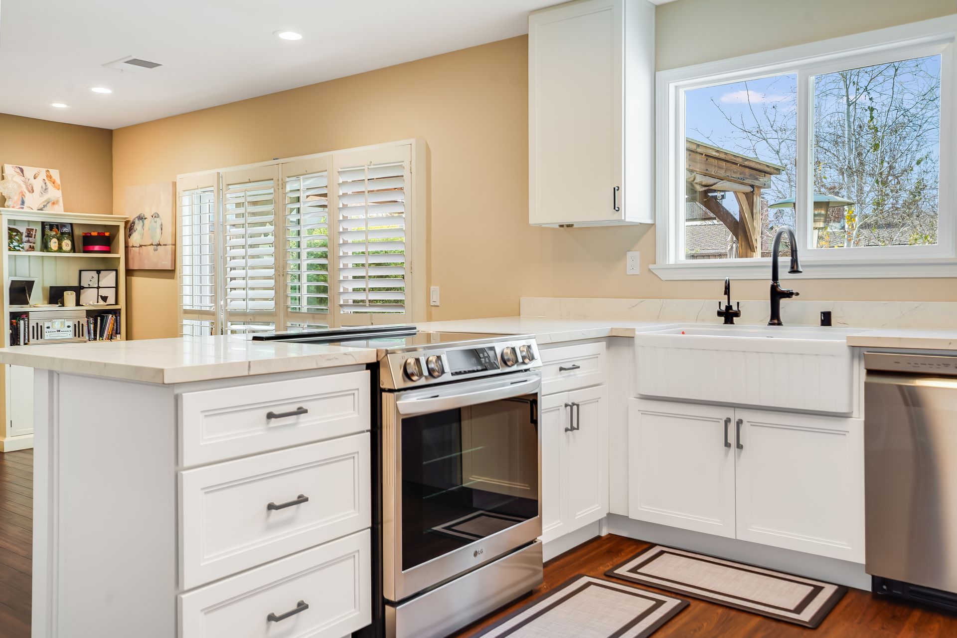 Bright kitchen with white cabinets, stainless stove, island, and sink by a sunny window