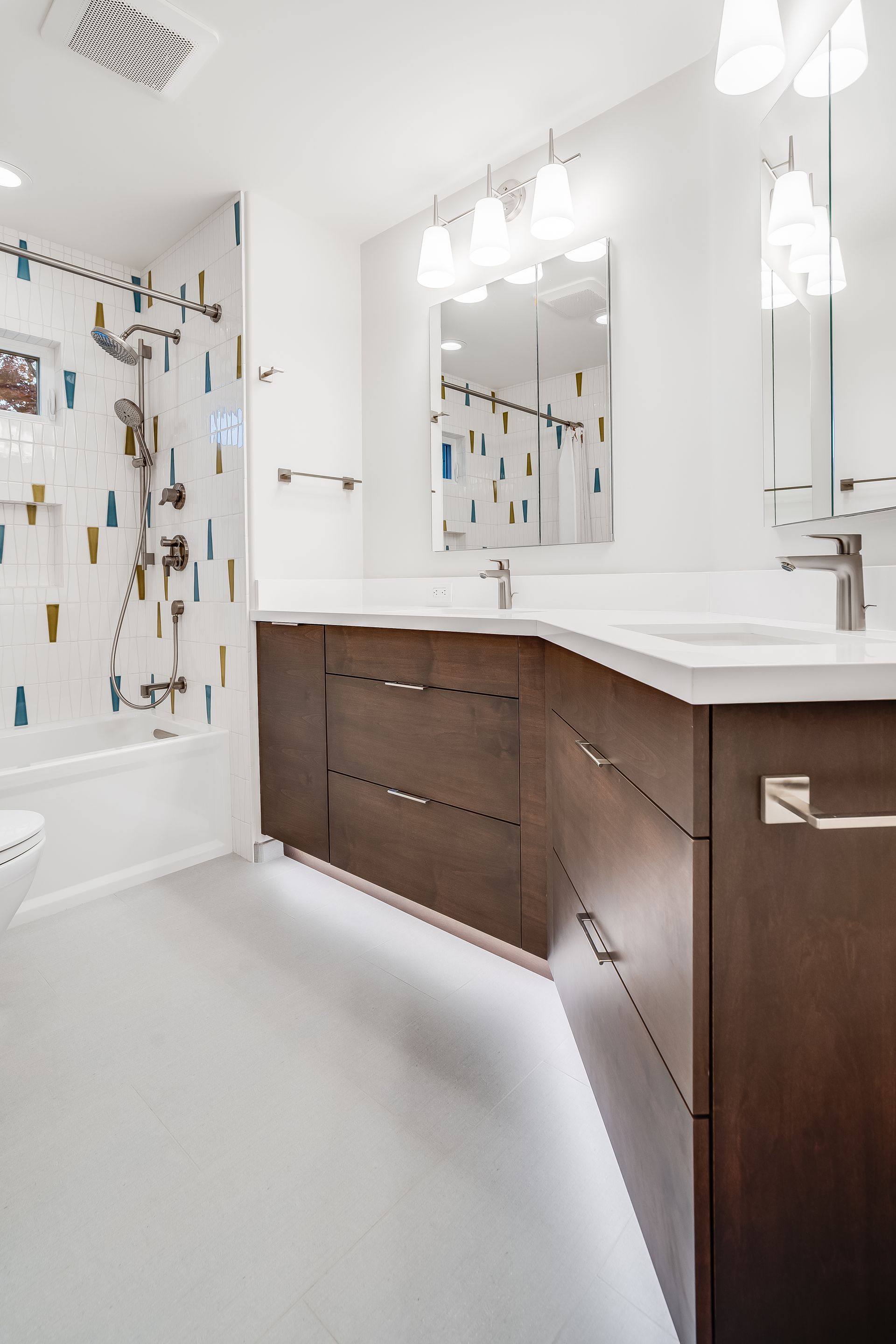 Modern bathroom with dark wood vanity, white countertops, mirrors, and a shower curtain in the background