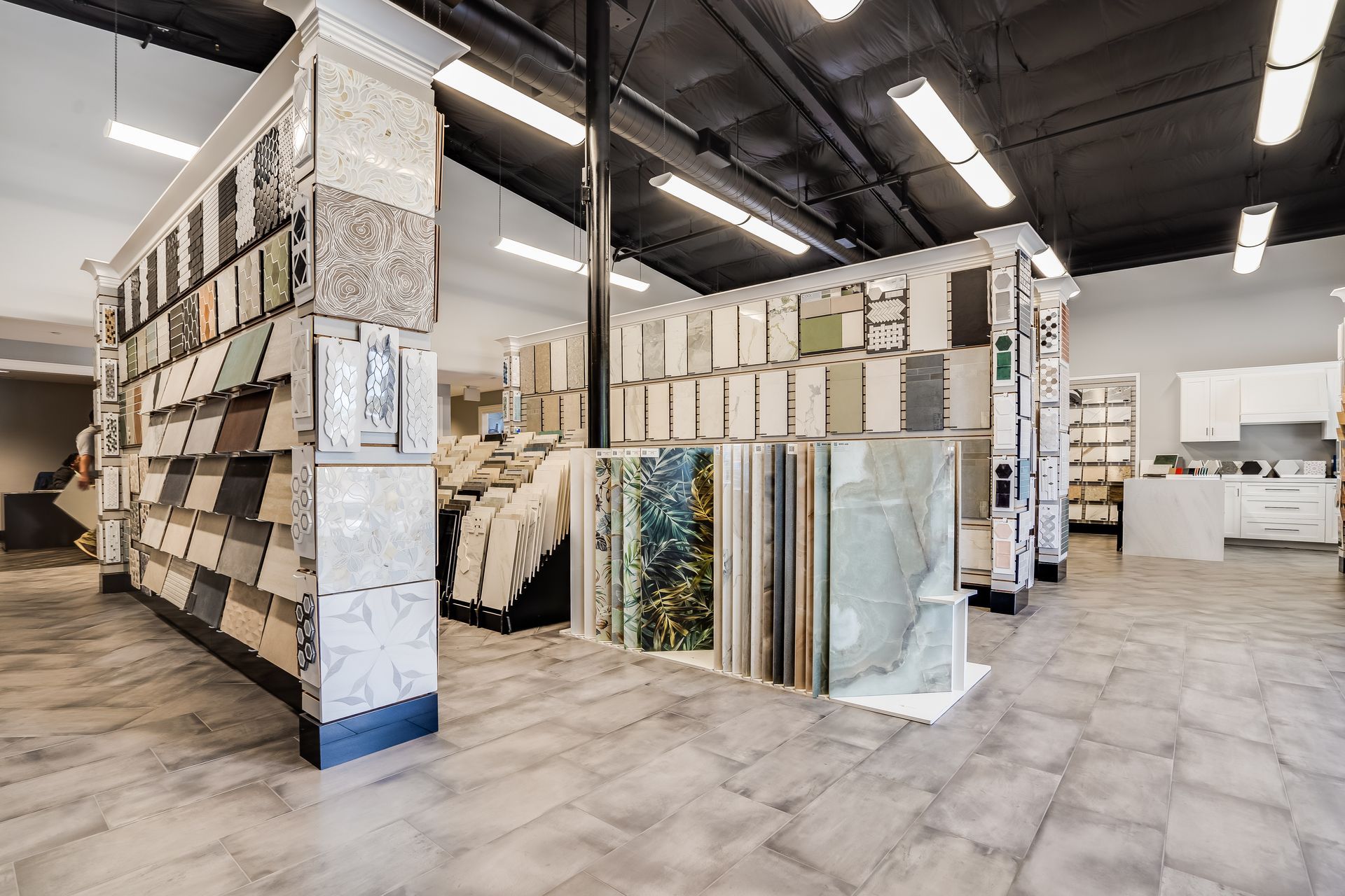 Tile showroom with large tile displays on shelves and samples arranged throughout a bright warehouse-style interior