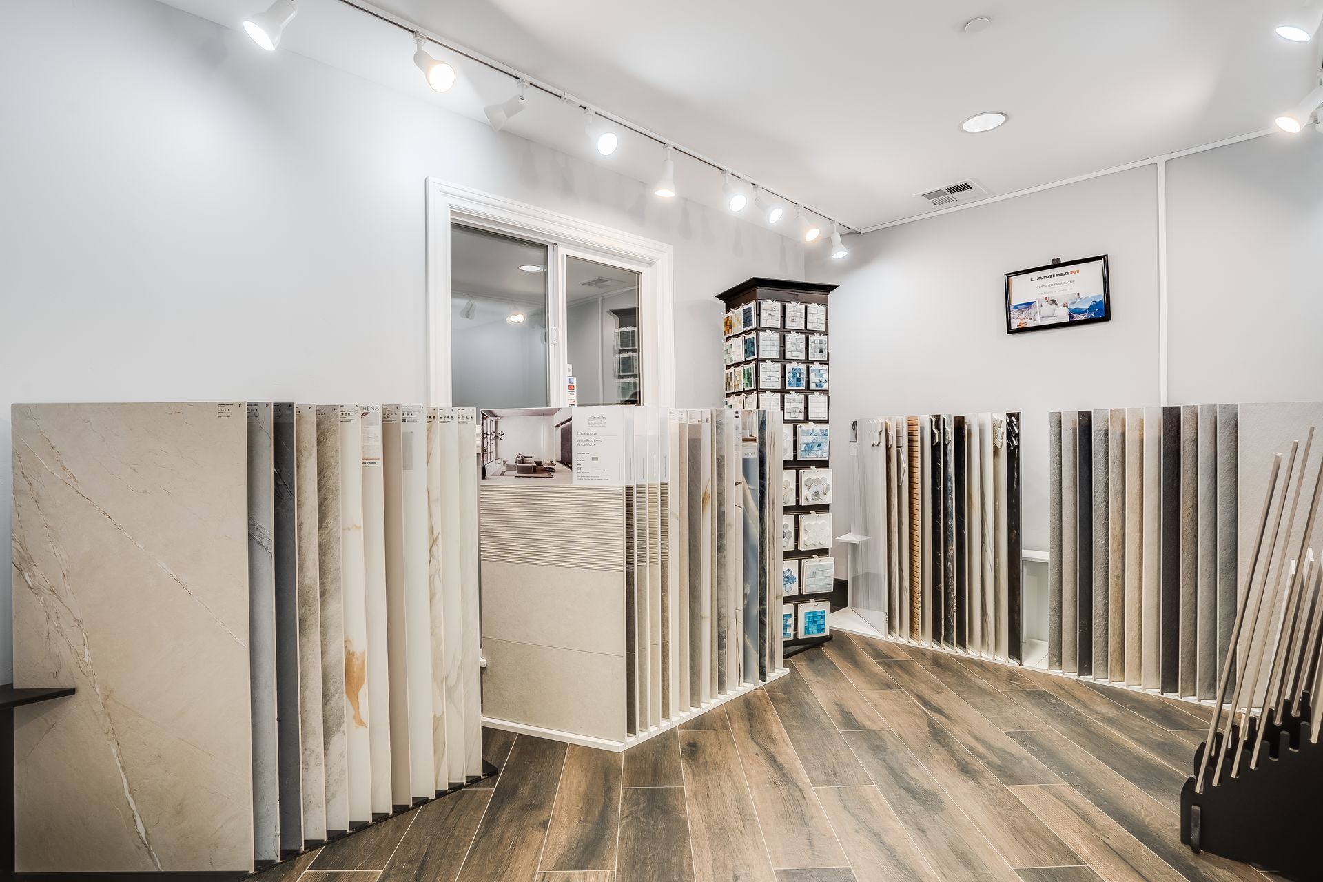 Bright flooring showroom with rows of large tile and stone samples along the walls
