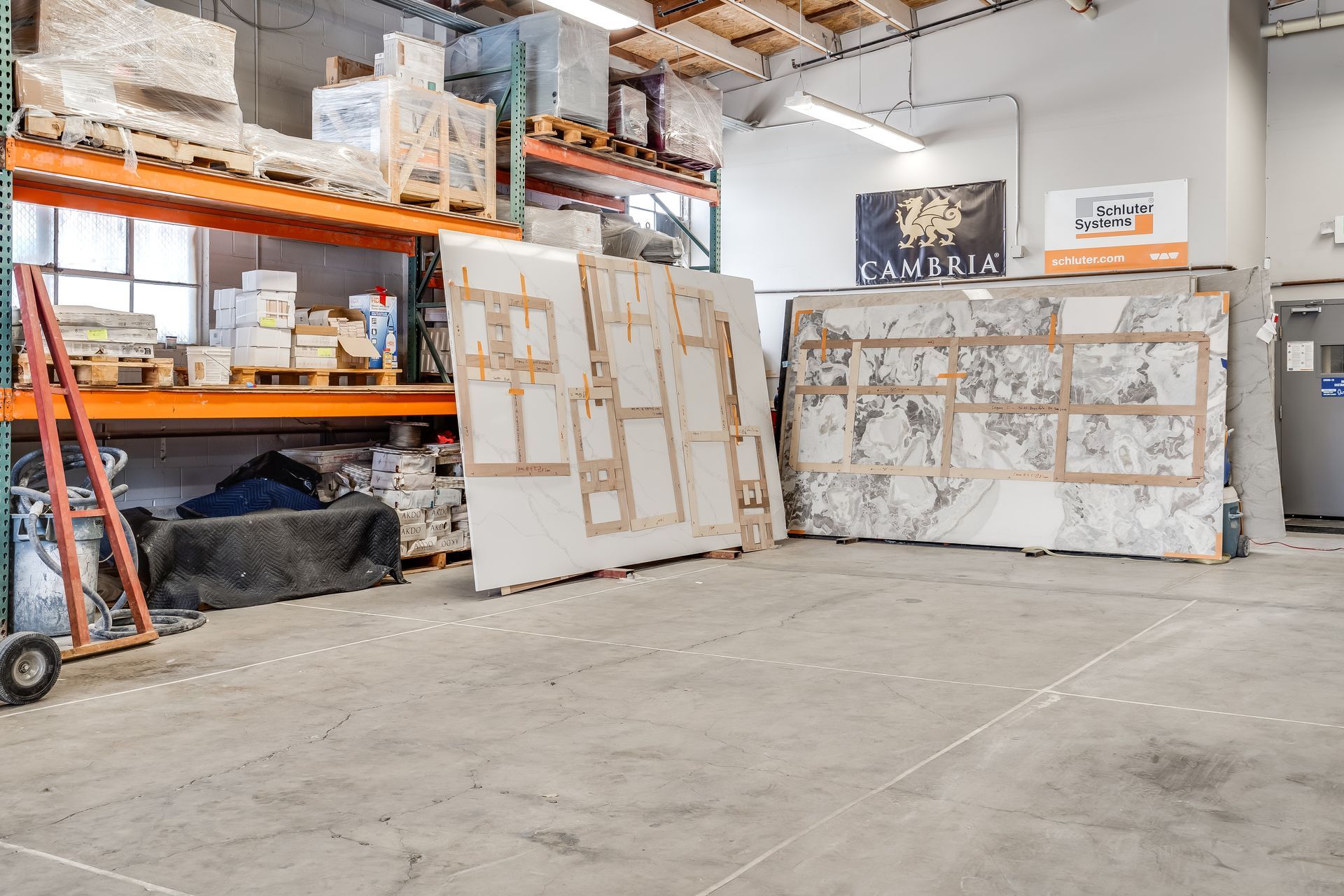 Warehouse with large framed canvases leaning against walls on a concrete floor