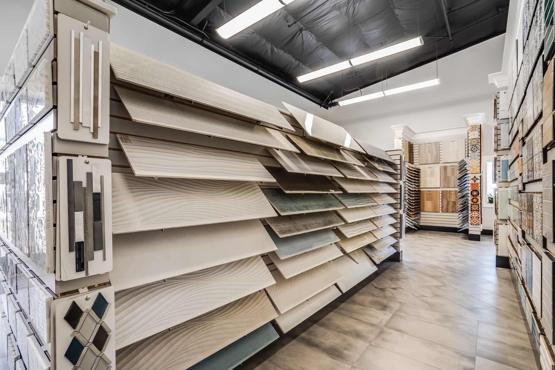 Aisle in a tile or flooring store with large beige and gray sample boards on display racks