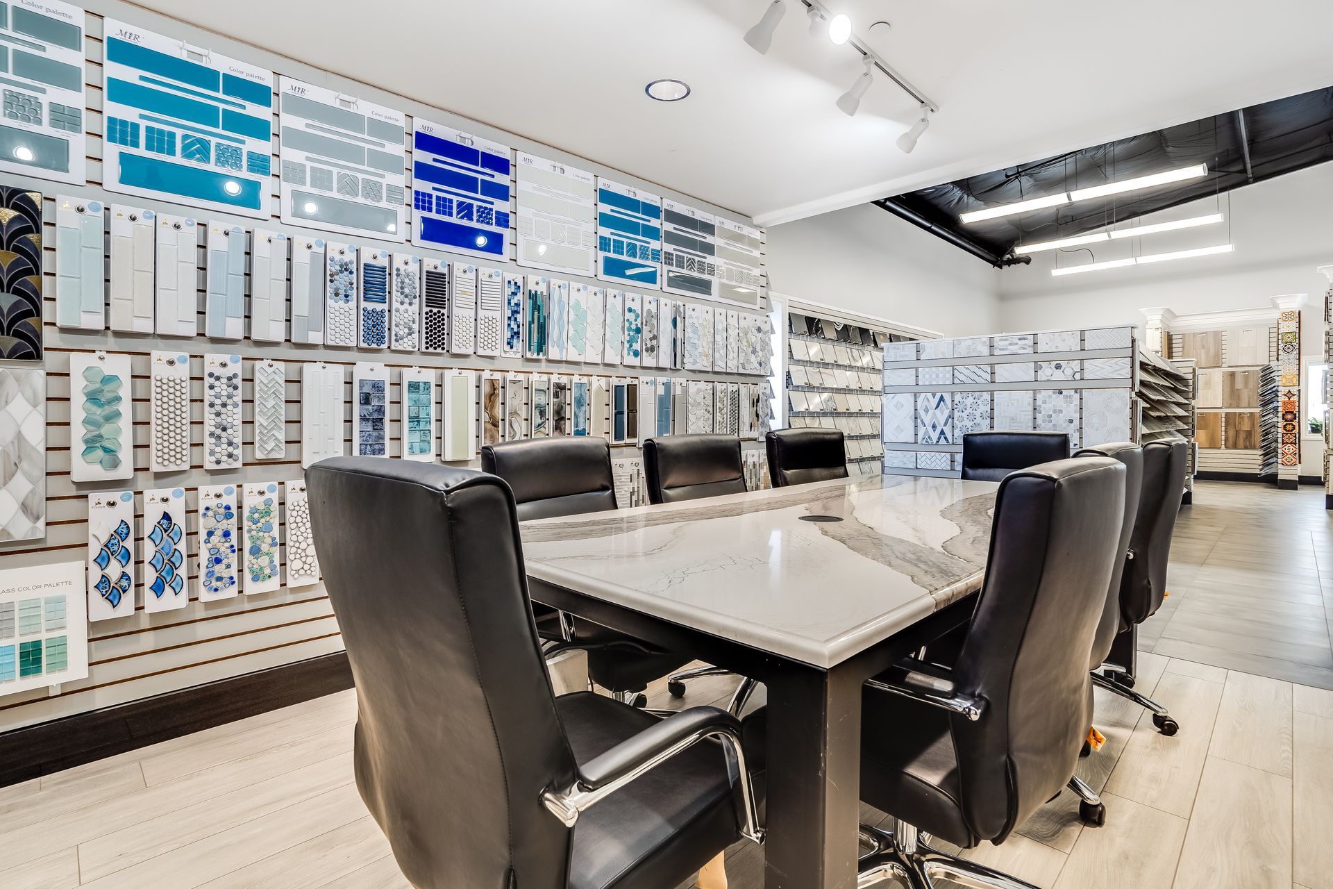 Modern showroom with display walls, a meeting table, and black chairs under bright ceiling lights