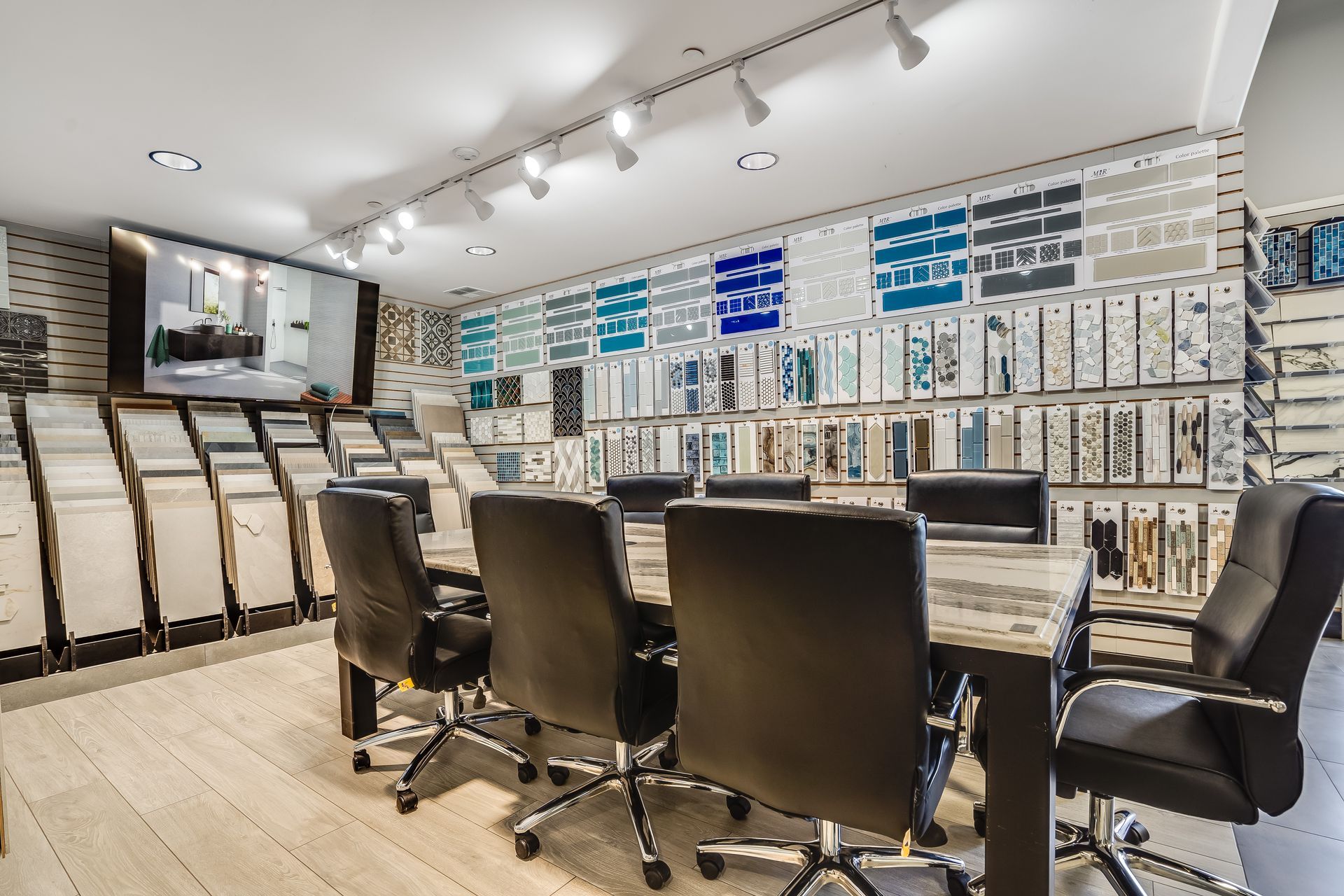 Modern office conference room with black chairs, wood table, and walls covered in organized binders and samples