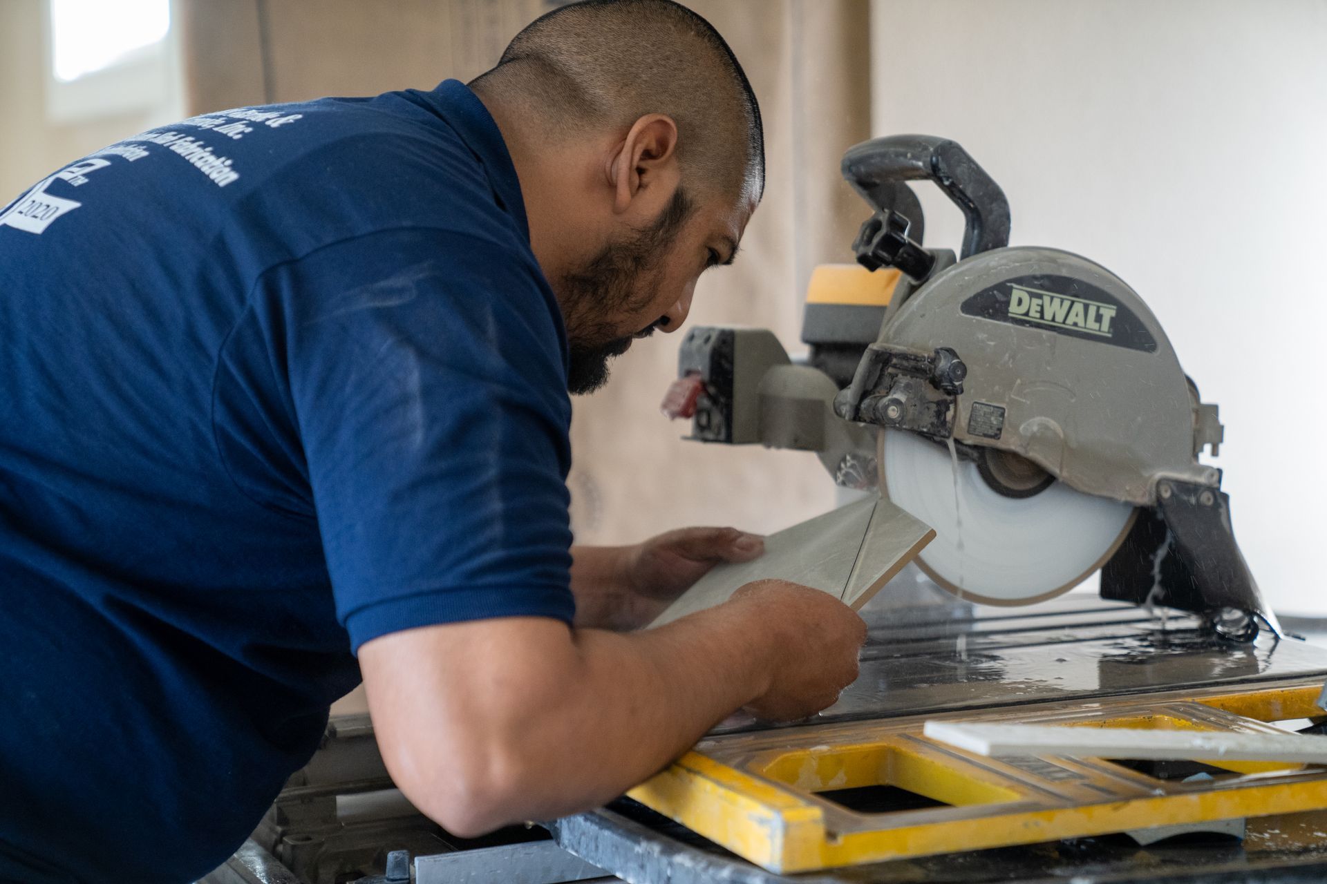 Man in blue shirt cutting material with a DeWalt miter saw in a workshop