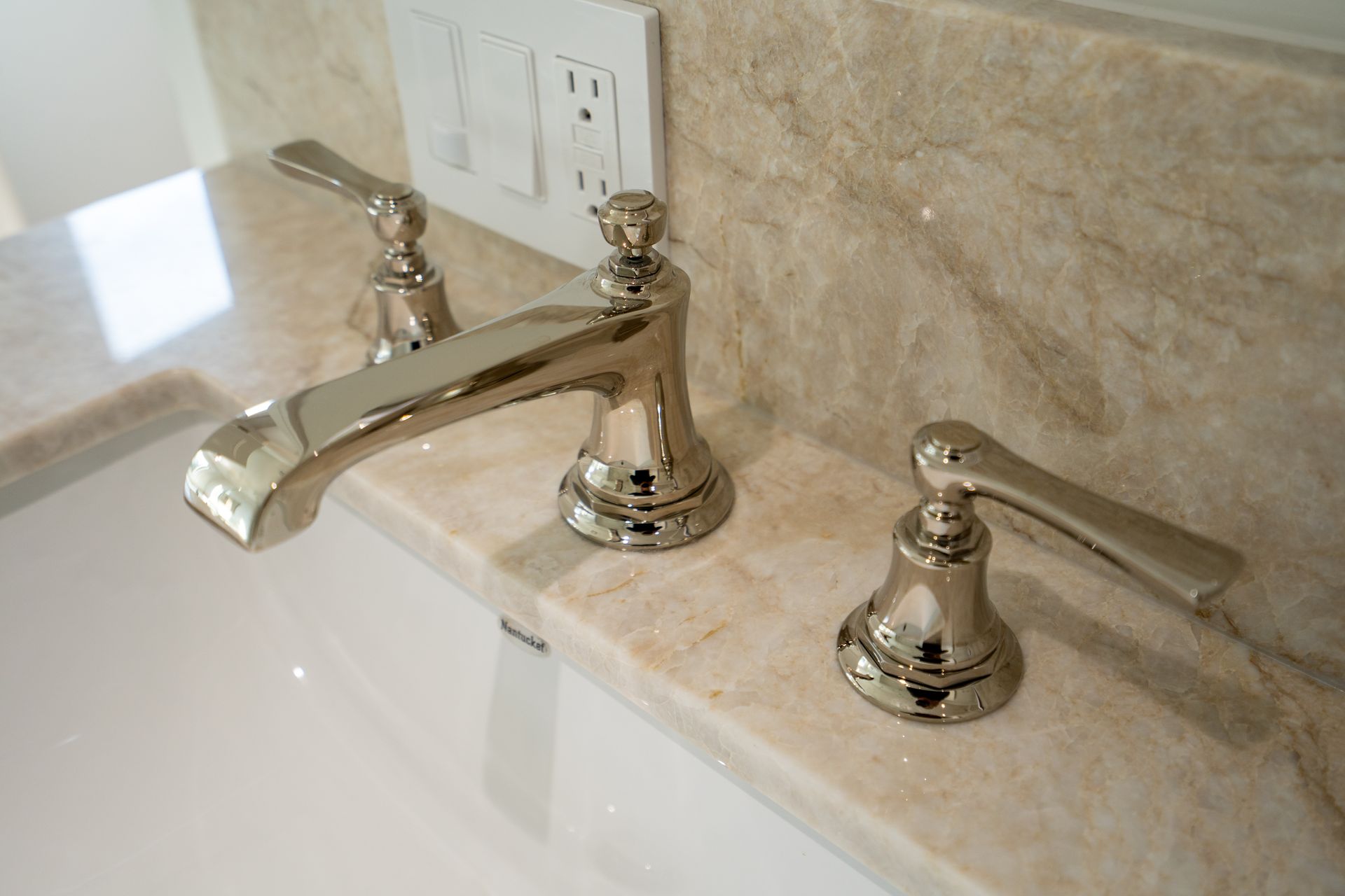 Chrome bathroom sink faucet with separate hot and cold handles on a marble countertop