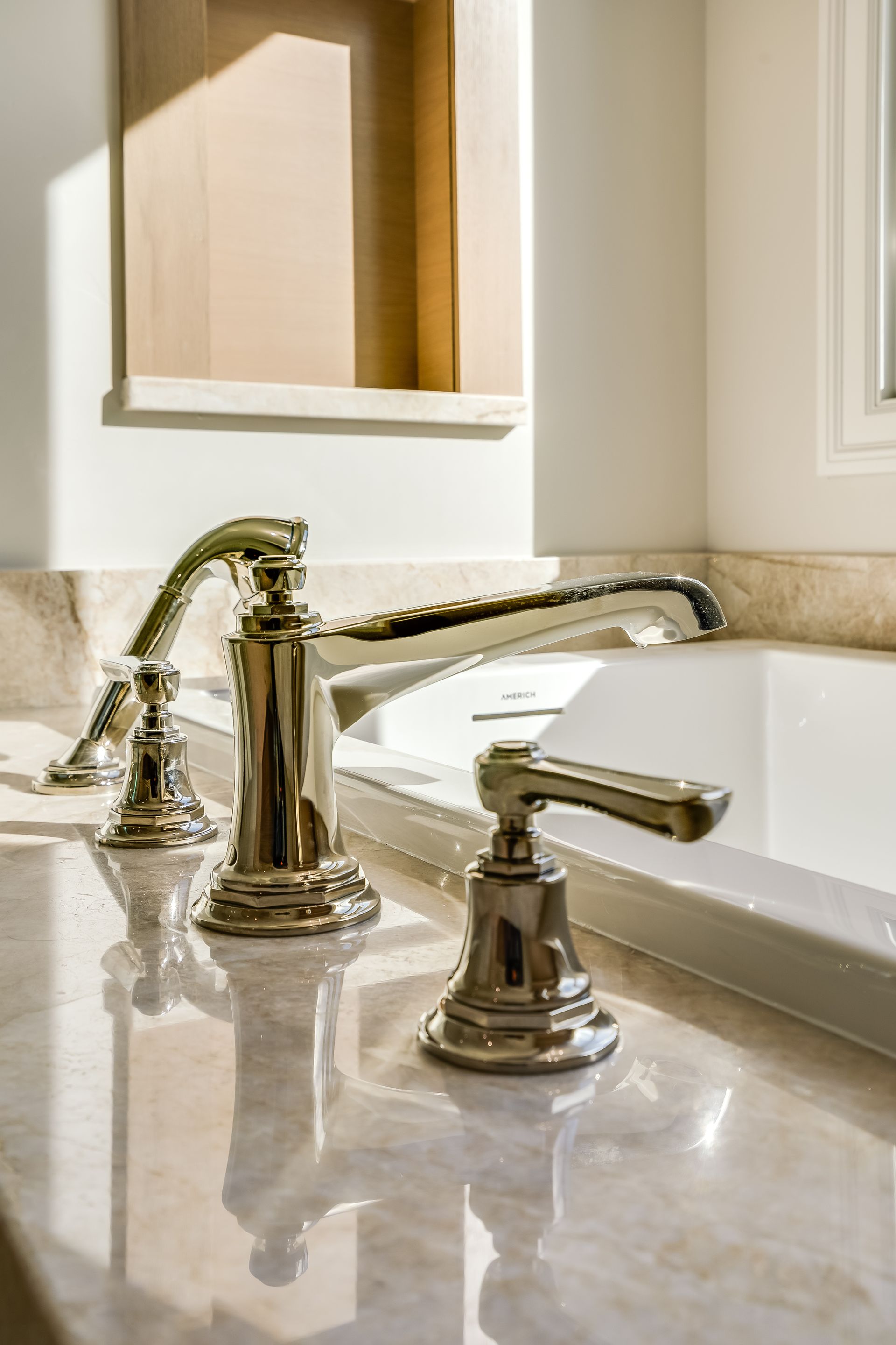 Polished bathroom sink with chrome faucet, marble countertop, and mirror reflecting warm light