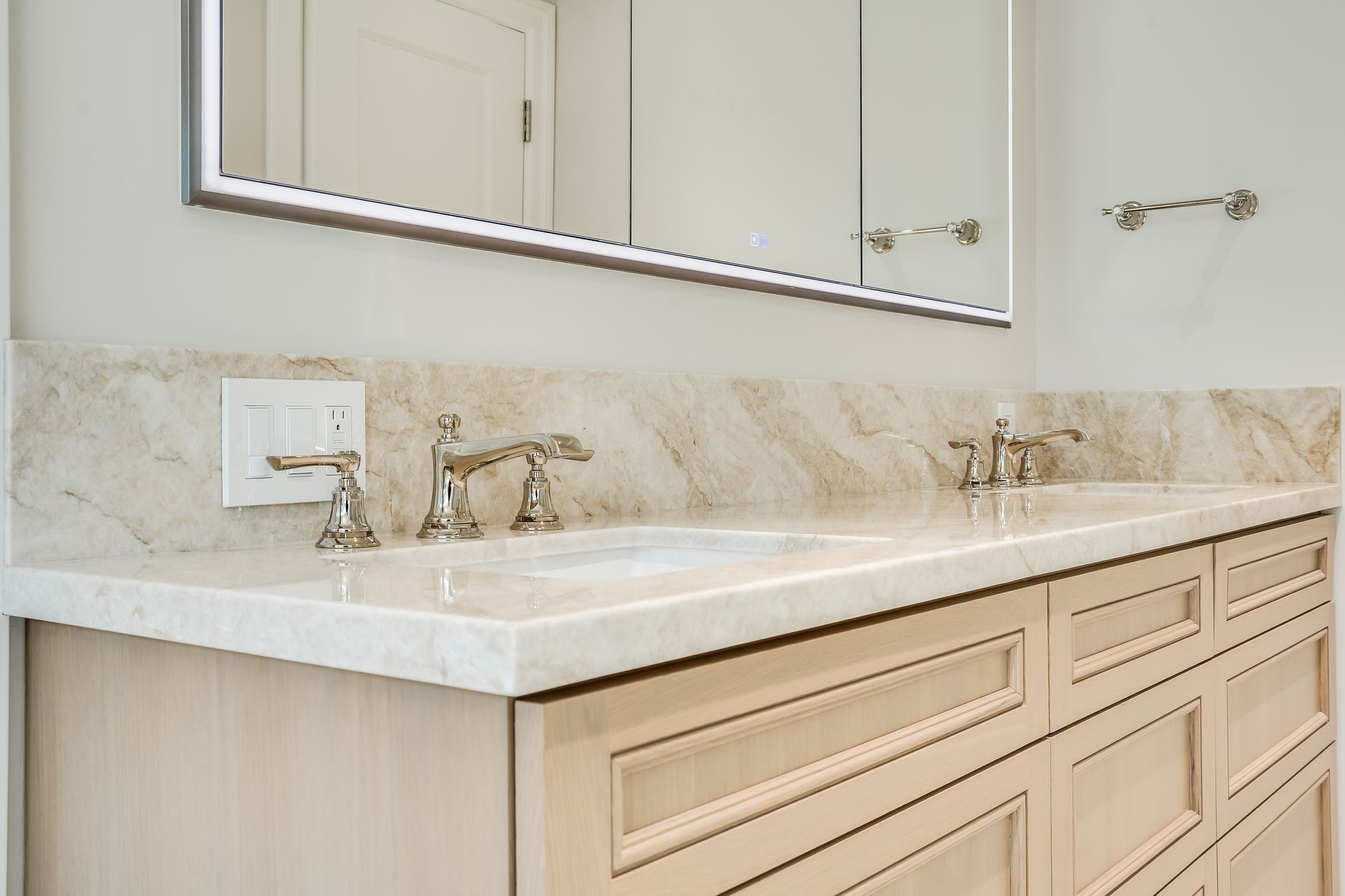 Beige bathroom vanity with marble countertop, double sinks, and a large mirror