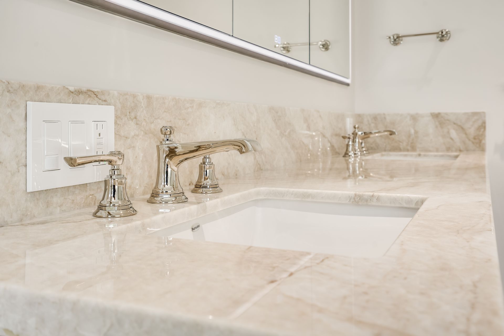 Beige marble bathroom vanity with sink, chrome faucet, and wall mirror