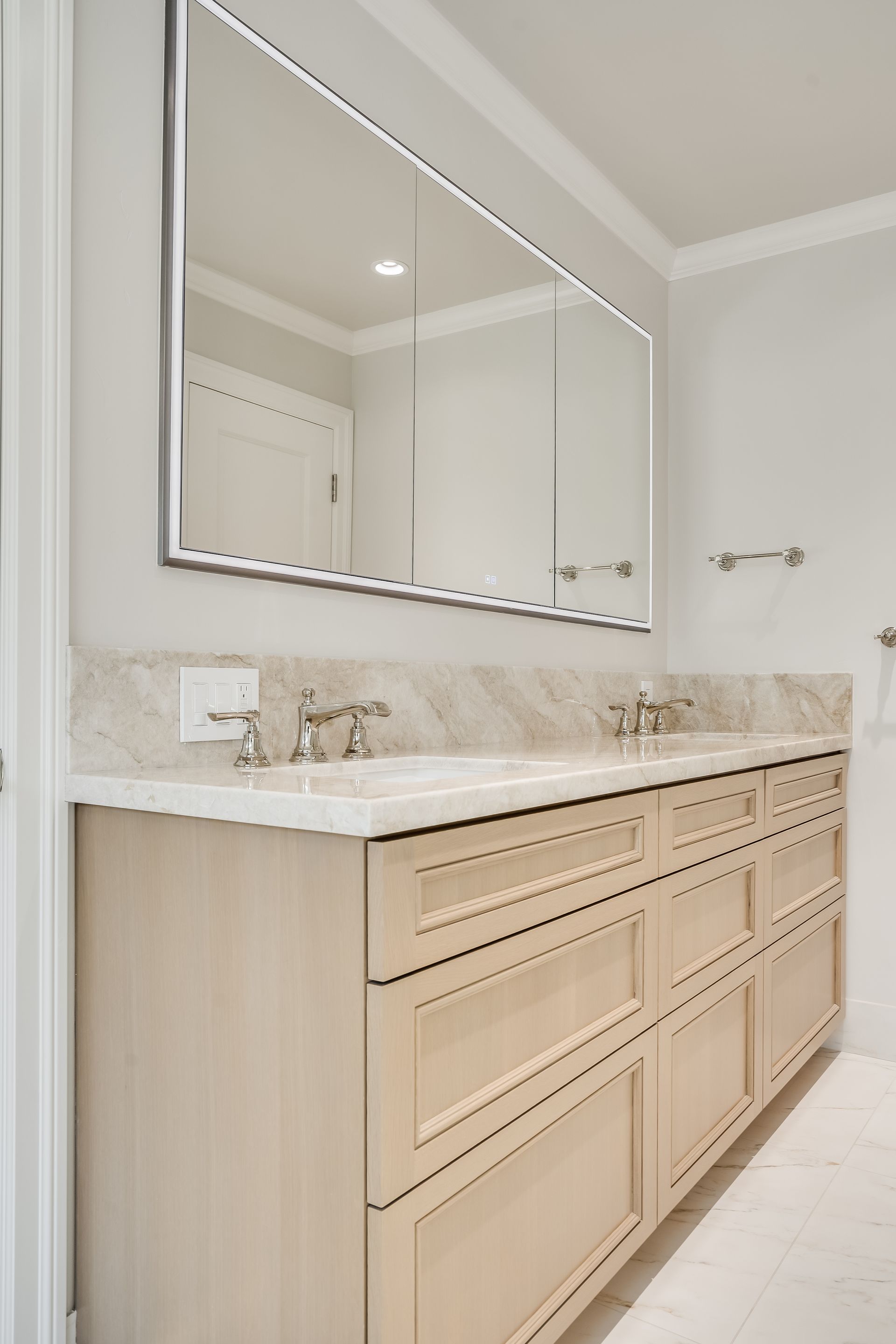 Bright bathroom vanity with marble countertop, large mirror, and light wood cabinets