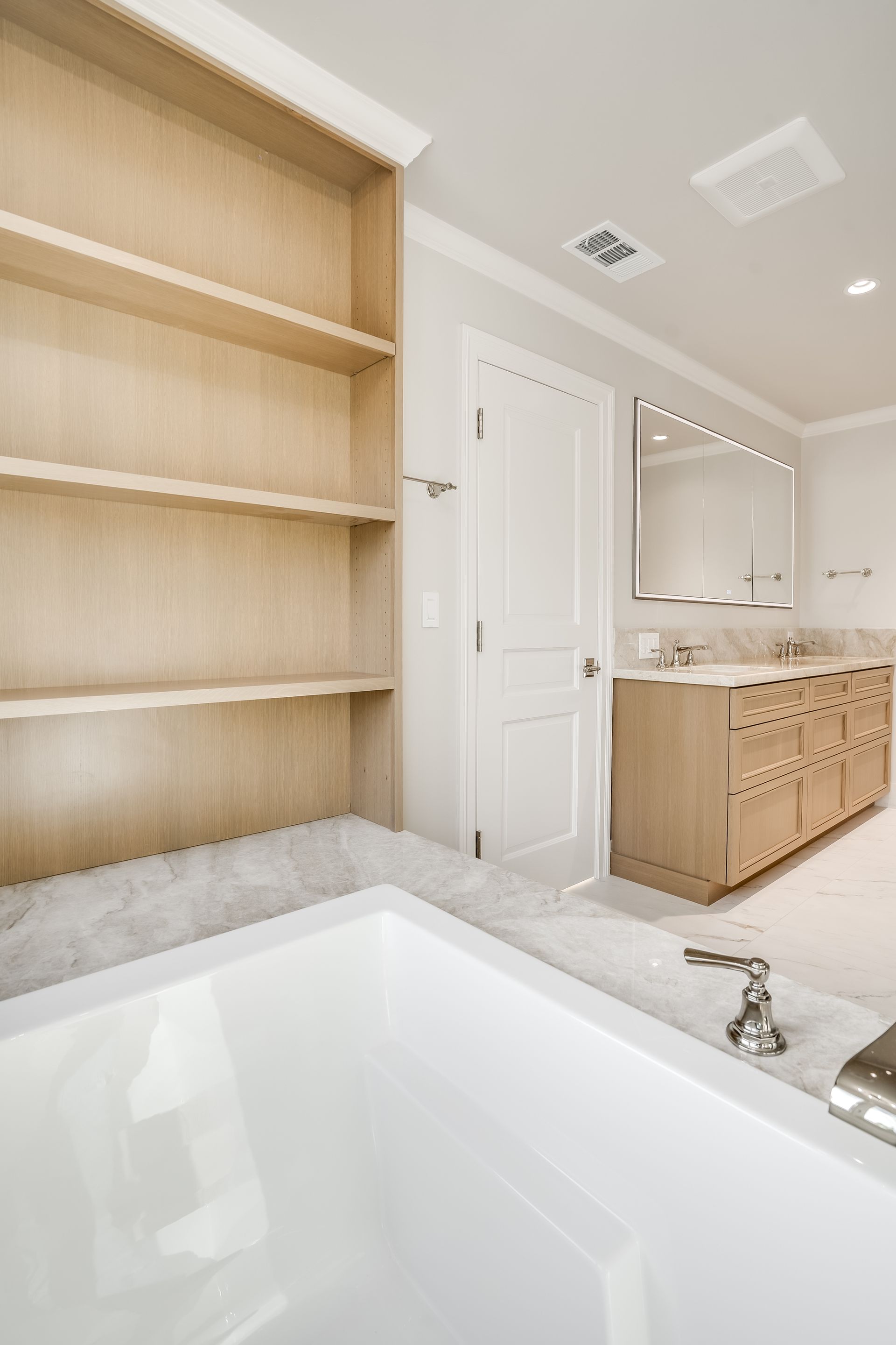 Modern bathroom with a freestanding tub, wood shelving, white vanity, and large mirror