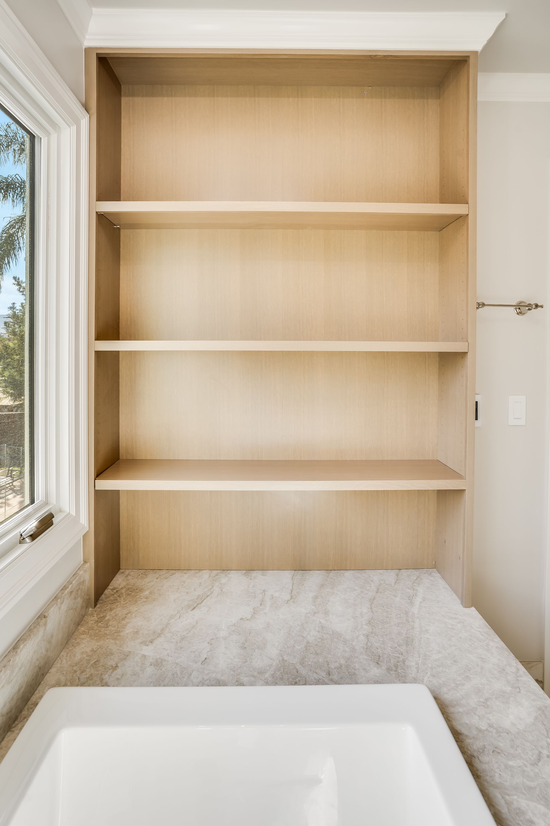 Built-in beige shelving in a bright alcove with a white counter in the foreground