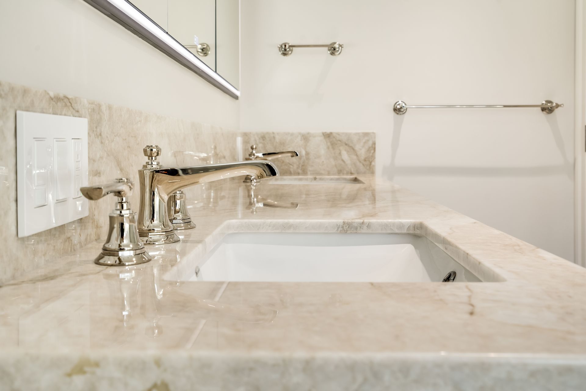 Bright bathroom vanity with white sink, chrome faucet, beige marble countertop, and wall mirror