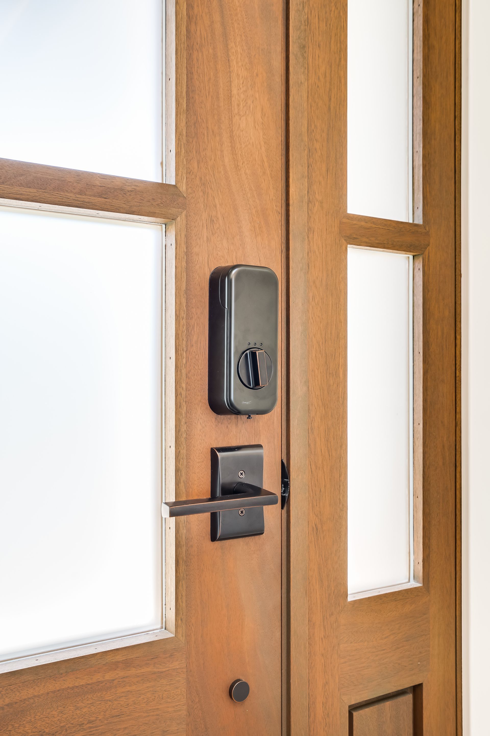 Wooden door with frosted glass panes, a black smart lock, and a matching handle.