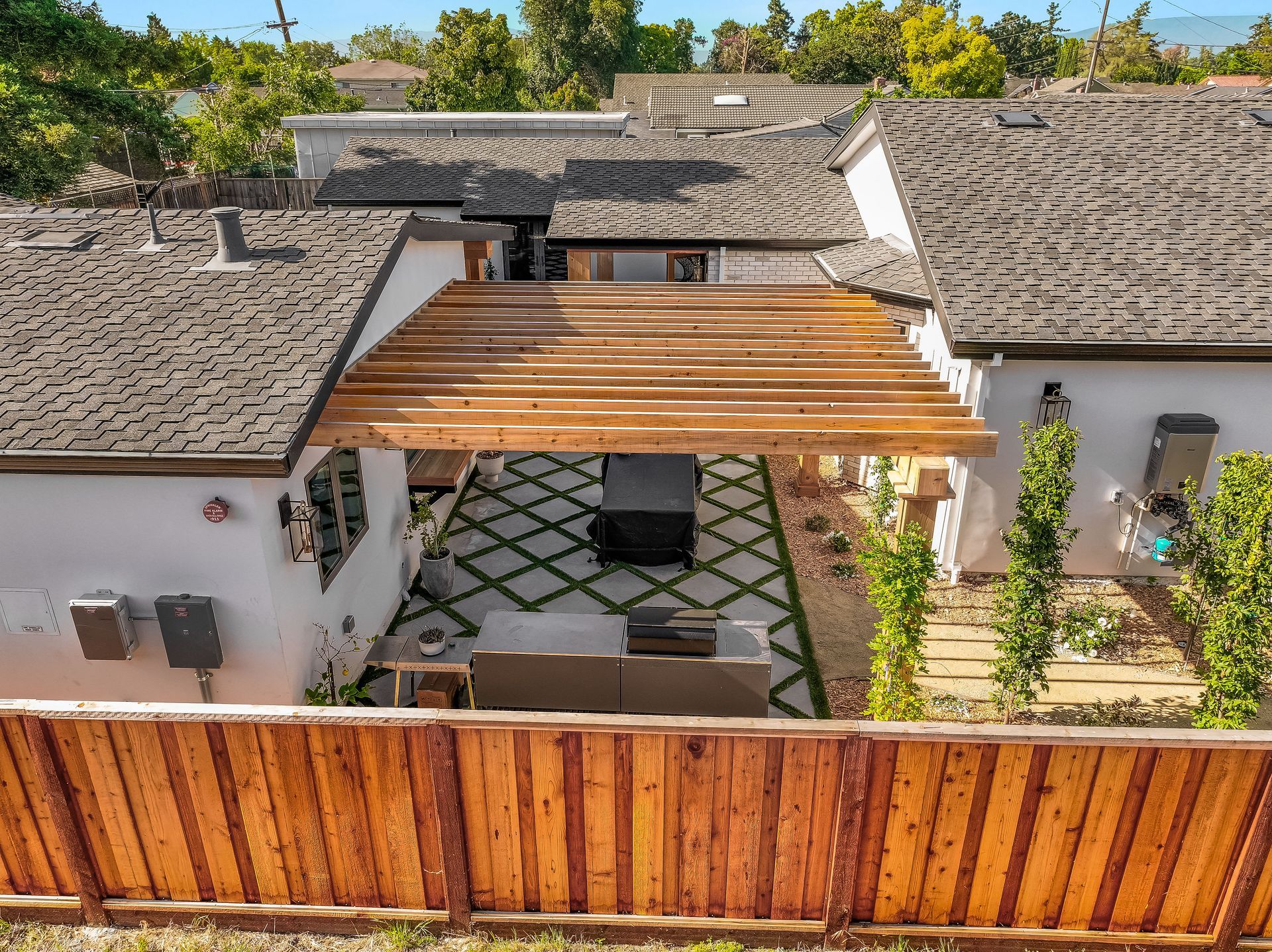 Courtyard with wooden pergola, tiled roofs, white walls, and a wooden fence in front