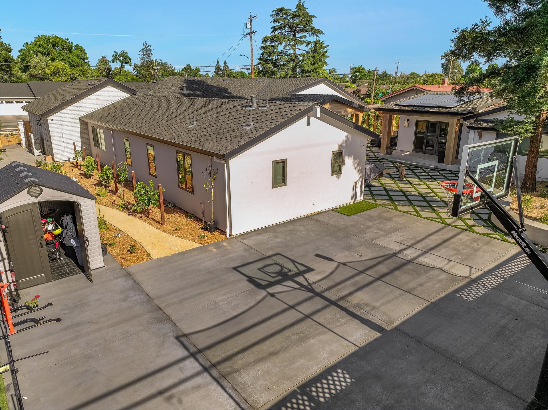 Aerial view of a house, driveway, and basketball hoop in a suburban neighborhood.