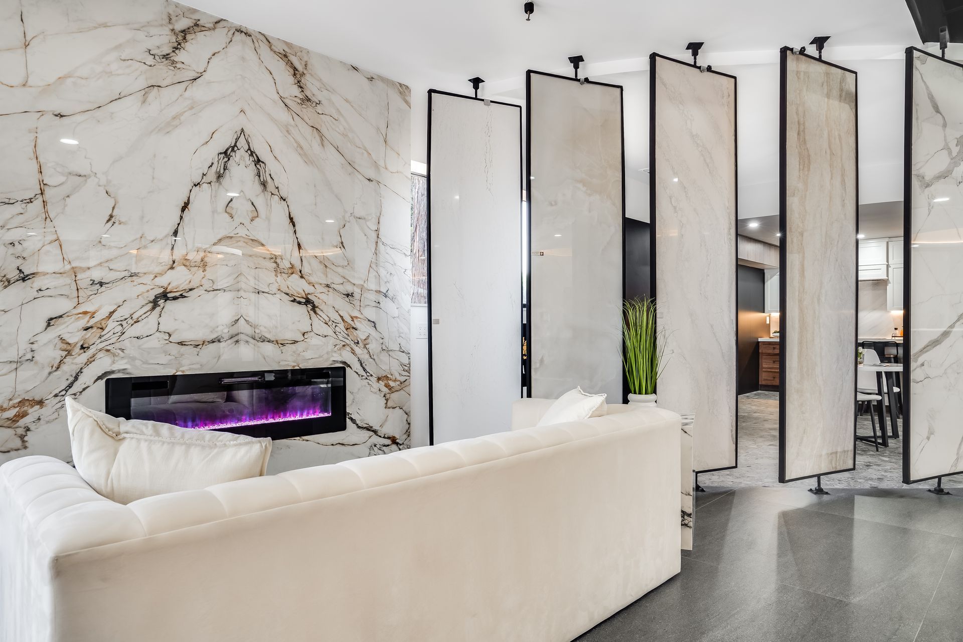 Modern living room with marble wall, white sofa, and tall mirrored panels