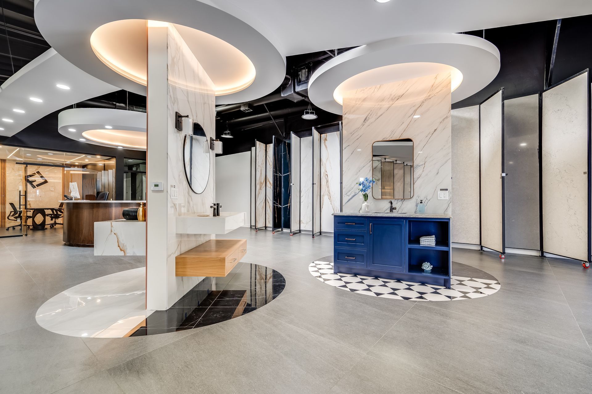 Modern showroom interior with marble columns, blue cabinetry, and circular ceiling lights