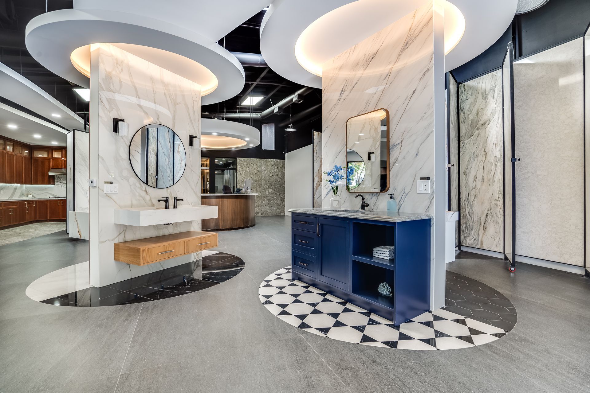 Modern showroom with sculptural circular displays, mirrors, and blue cabinetry on patterned flooring
