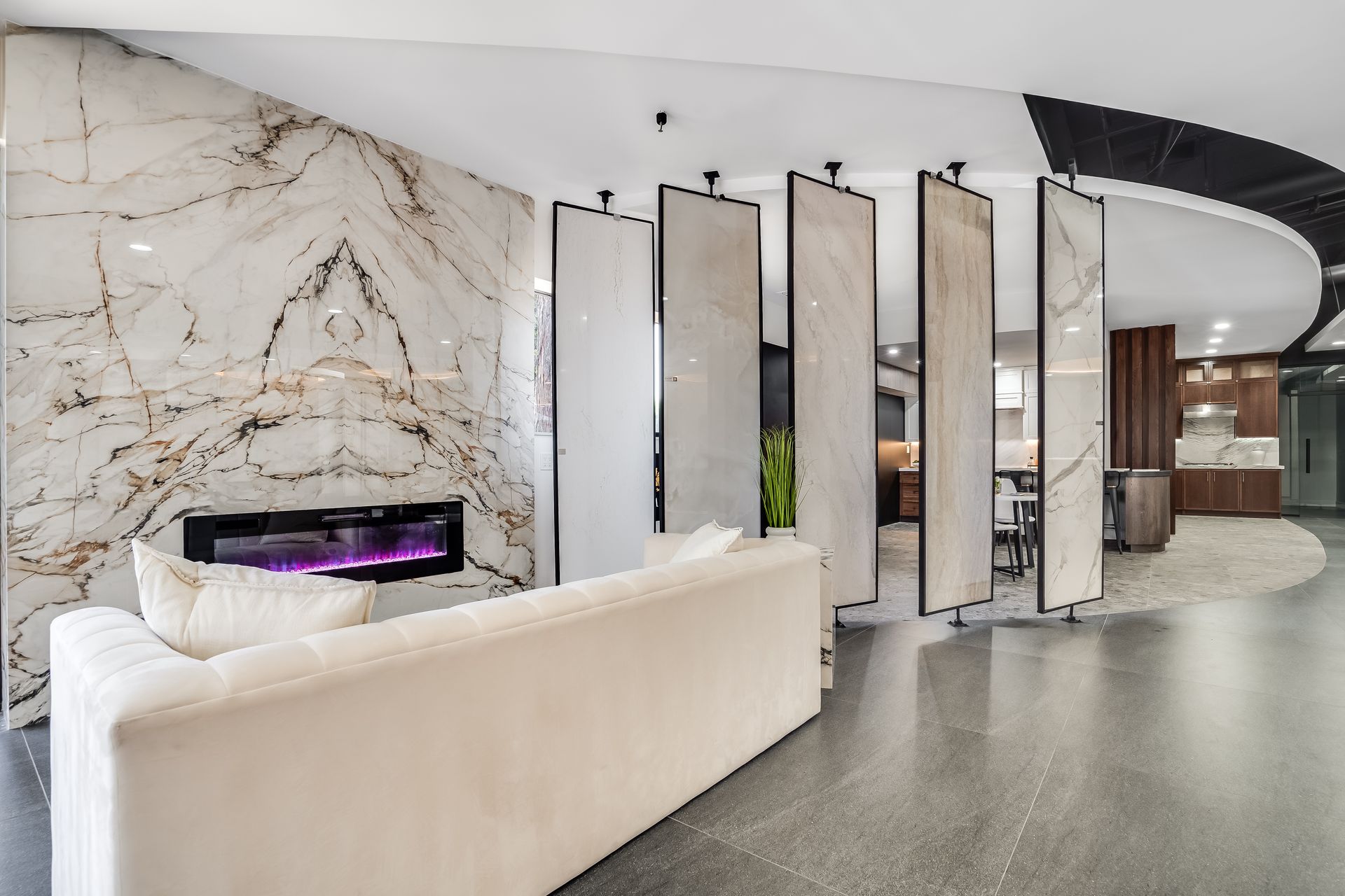Modern lobby with marble fireplace, white sofa, and tall mirrored panels in a sleek curved interior