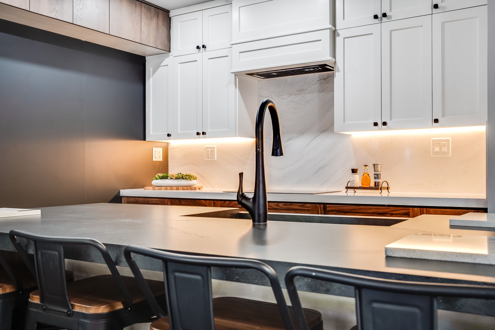 Modern kitchen with white cabinets, wooden island, black faucet, and two black bar stools