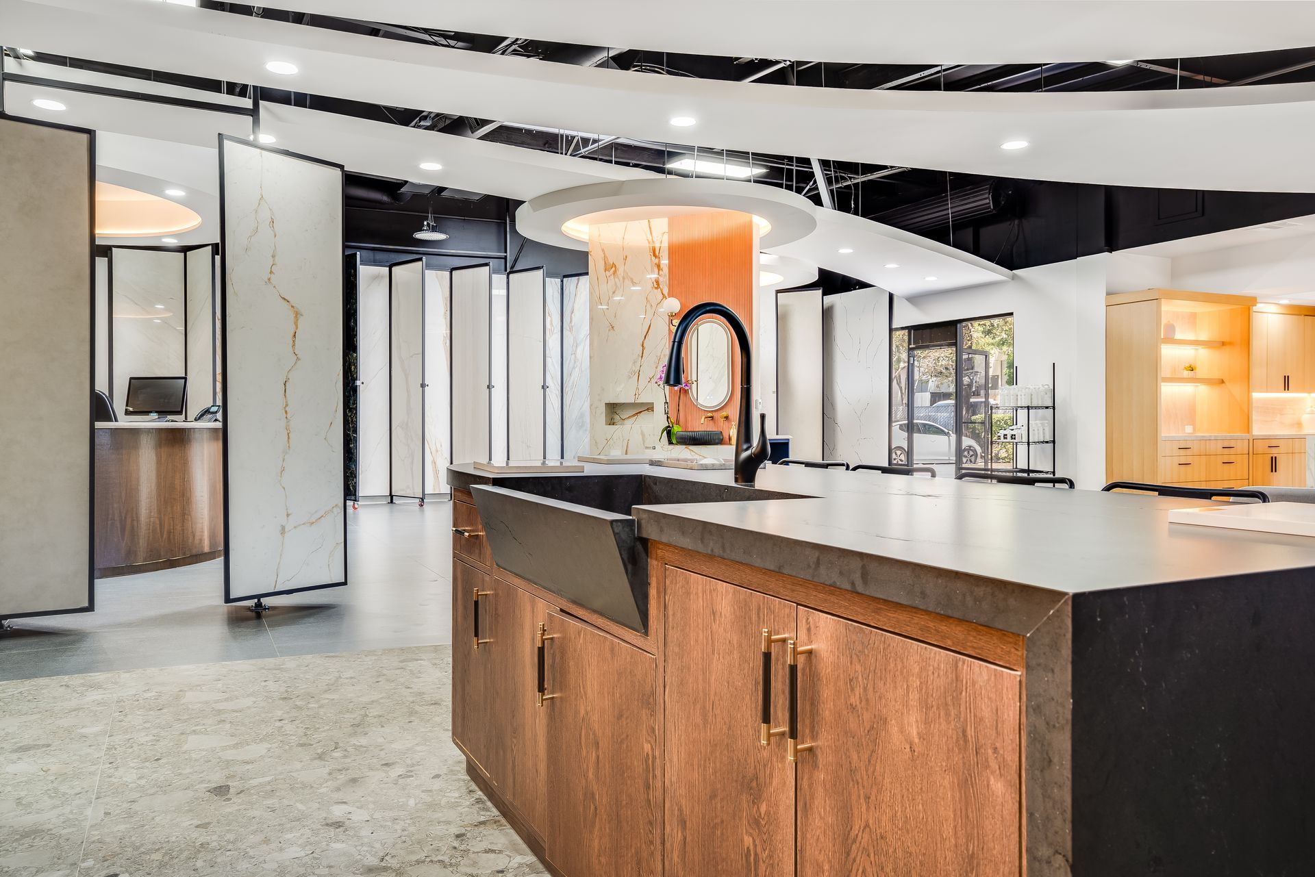 Modern open-concept kitchen with white cabinets, dark island, and orange pendant lighting
