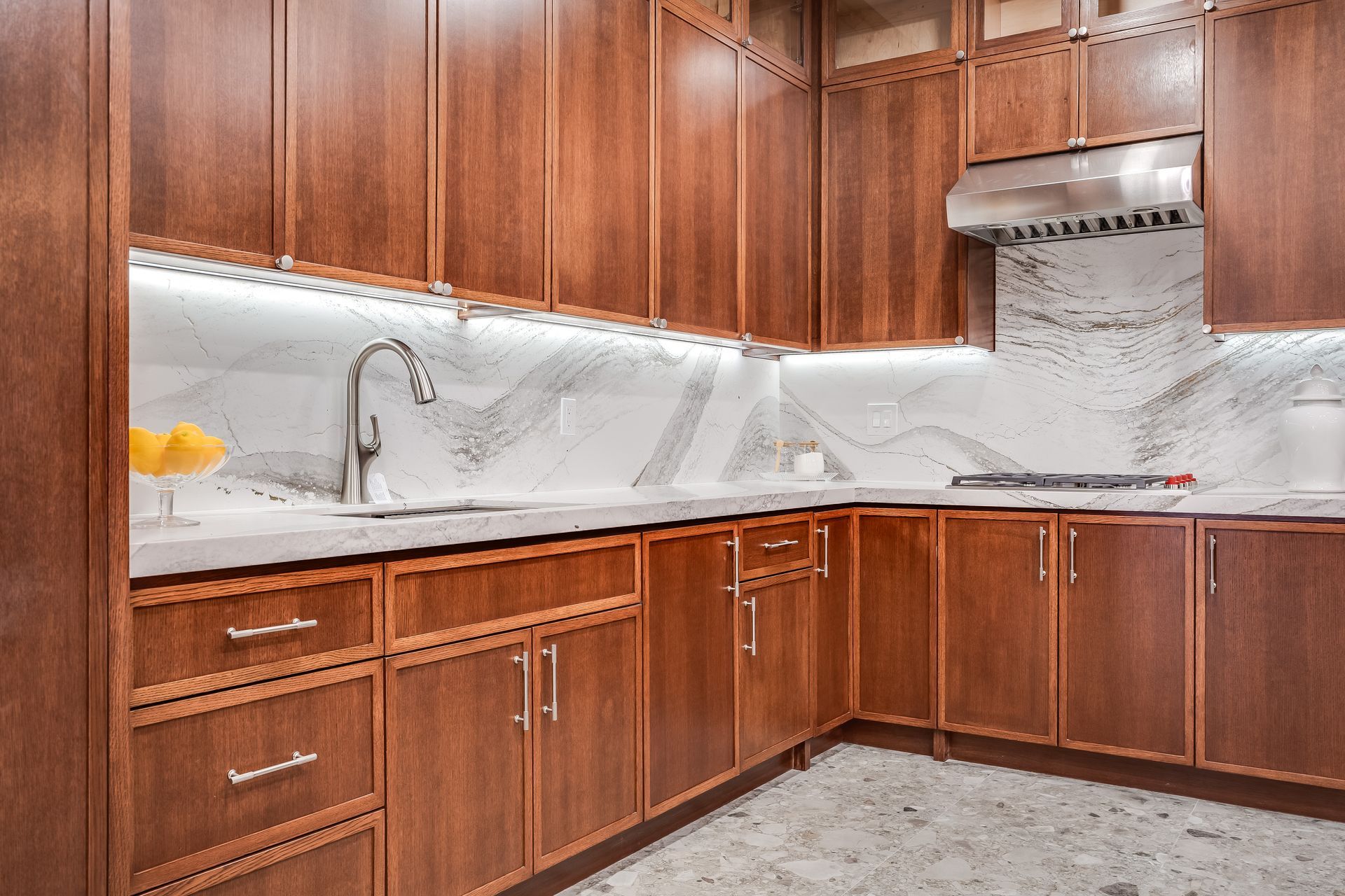 Modern kitchen with wood cabinets, white marble backsplash, and stainless steel range hood