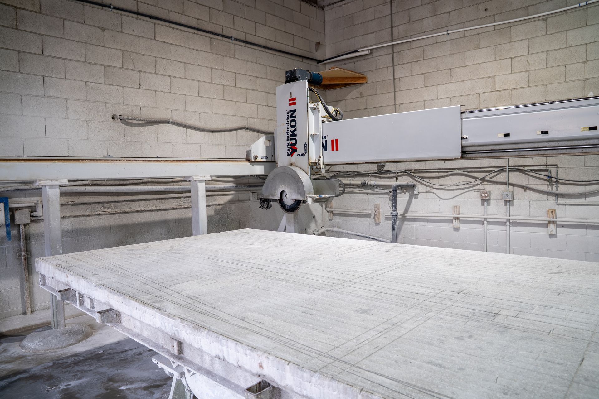 Industrial saw cutting a large white stone slab in a workshop