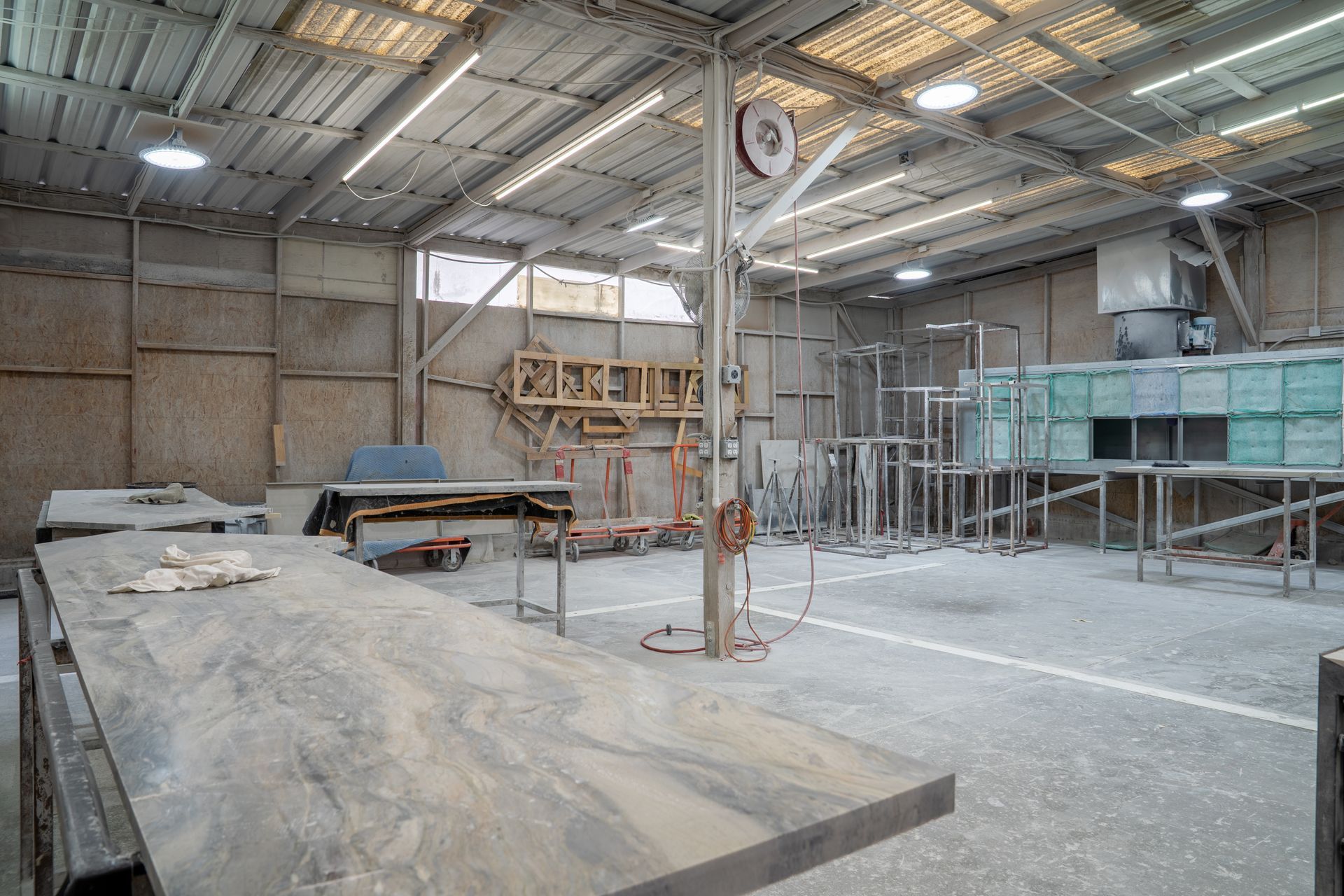 Large unfinished industrial warehouse interior with concrete floor, metal framing, and construction materials.