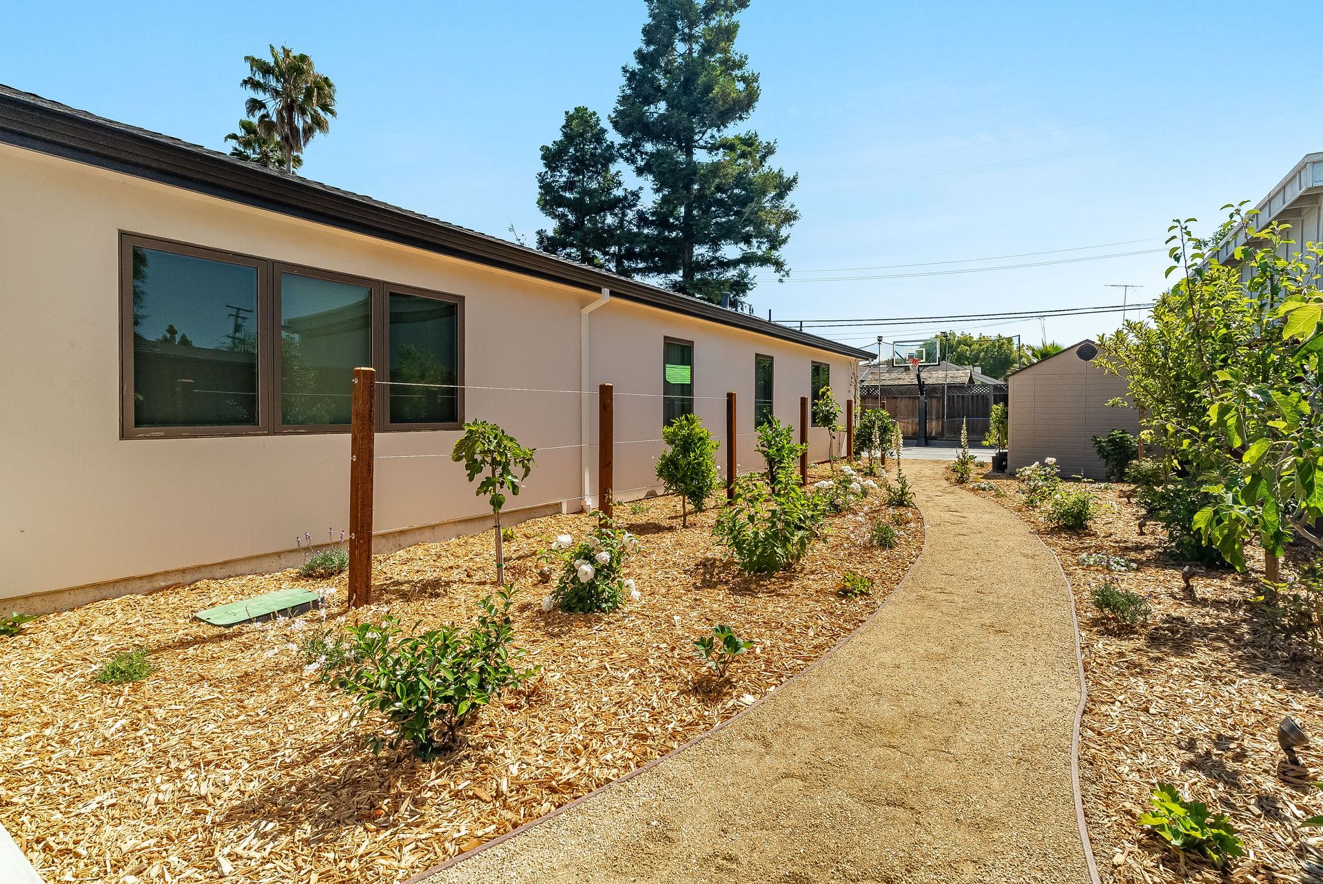 Single-story beige house with a gravel path and desert landscaping under a clear sky