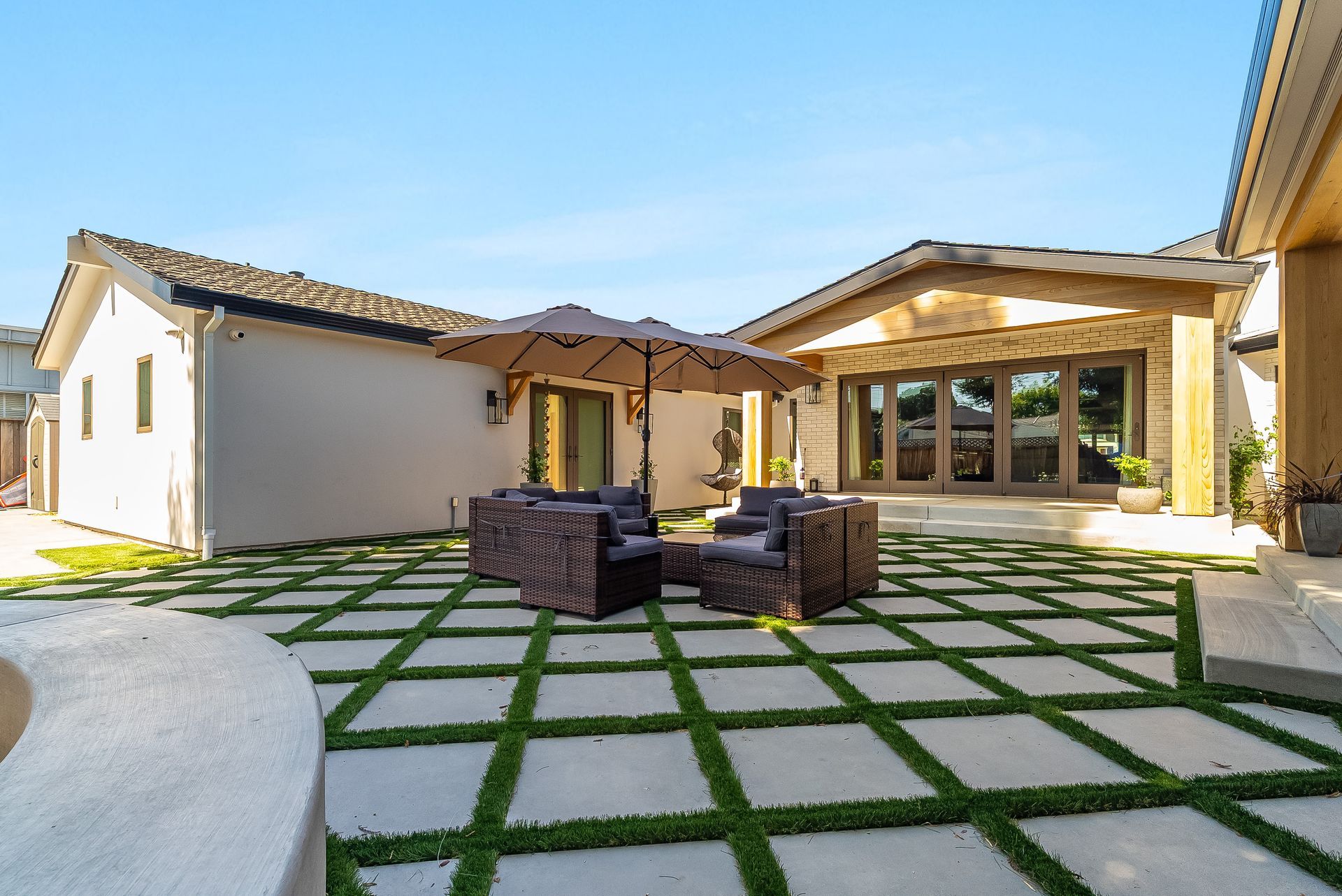Modern house patio with outdoor seating and large tiled courtyard in bright sunlight