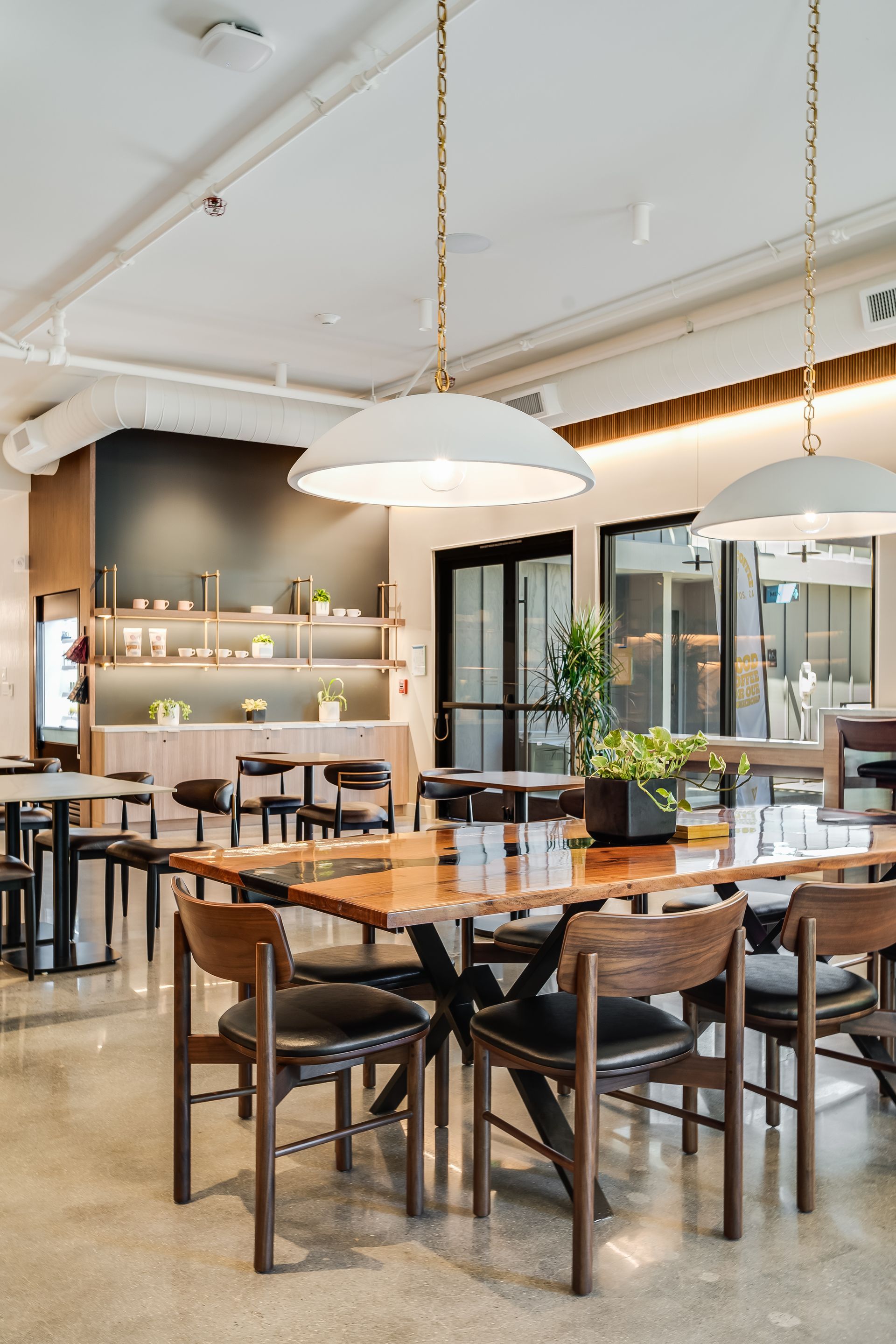 Modern restaurant dining area with wooden tables, chairs, and large pendant lights