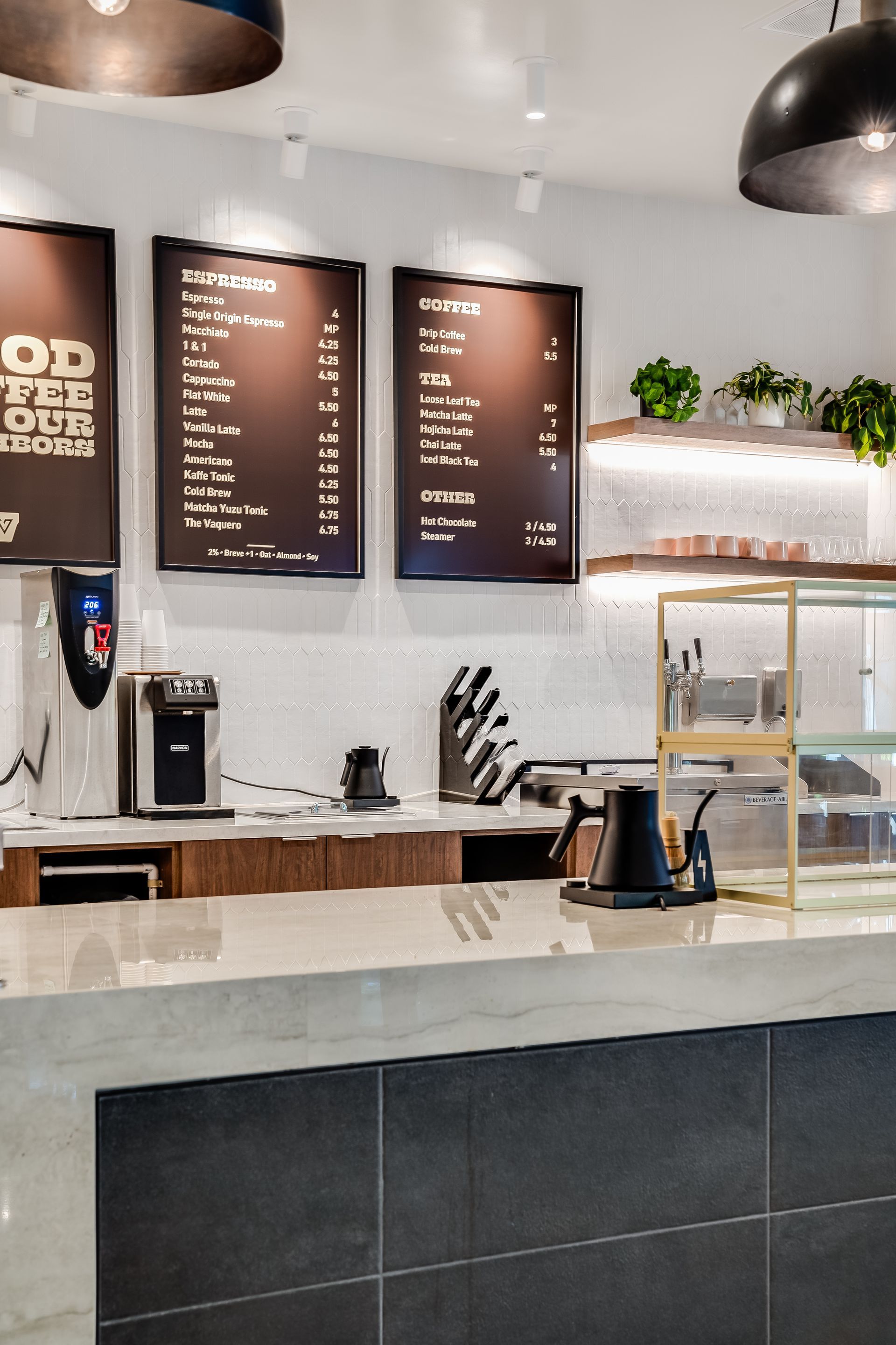 Modern coffee shop counter with menu boards, espresso machine, and pastry display cases