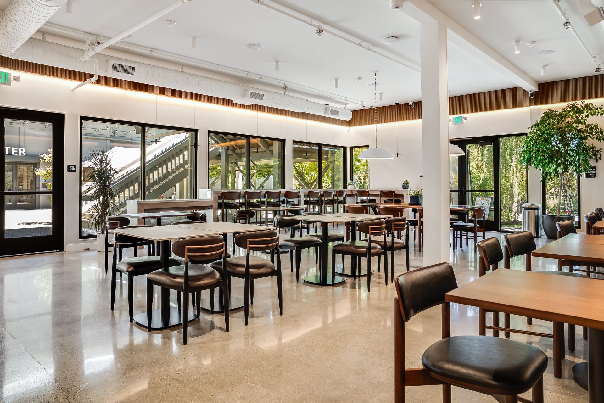 Bright modern café interior with tables, chairs, large windows, and polished floors
