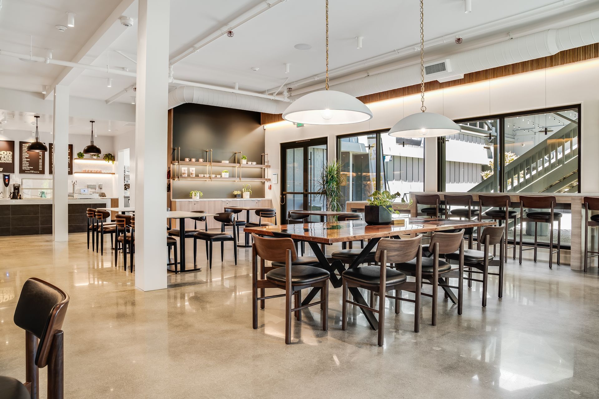 Bright modern restaurant interior with wooden tables, bar seating, and large windows