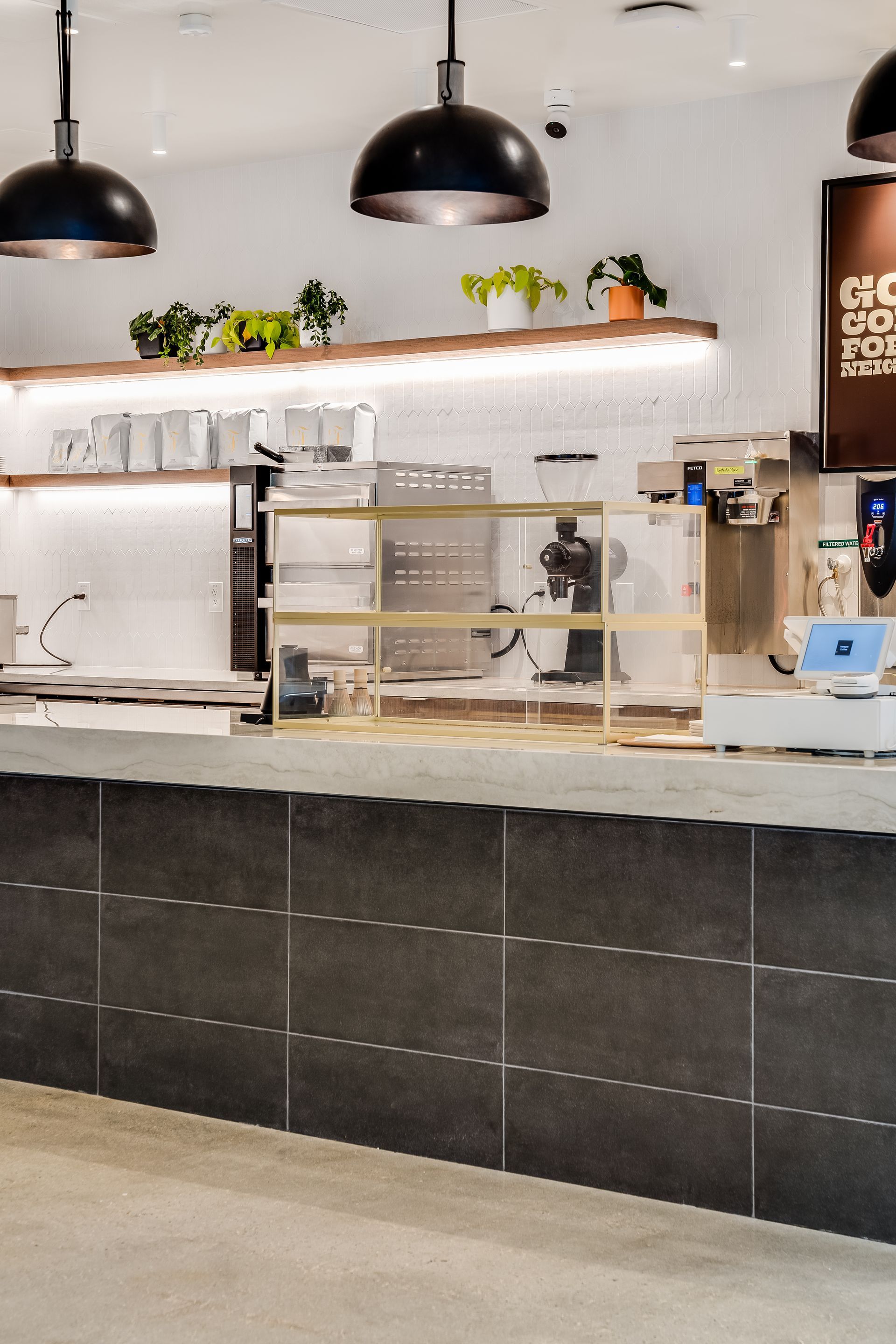 Modern café counter with espresso machines, pastries, and black pendant lights