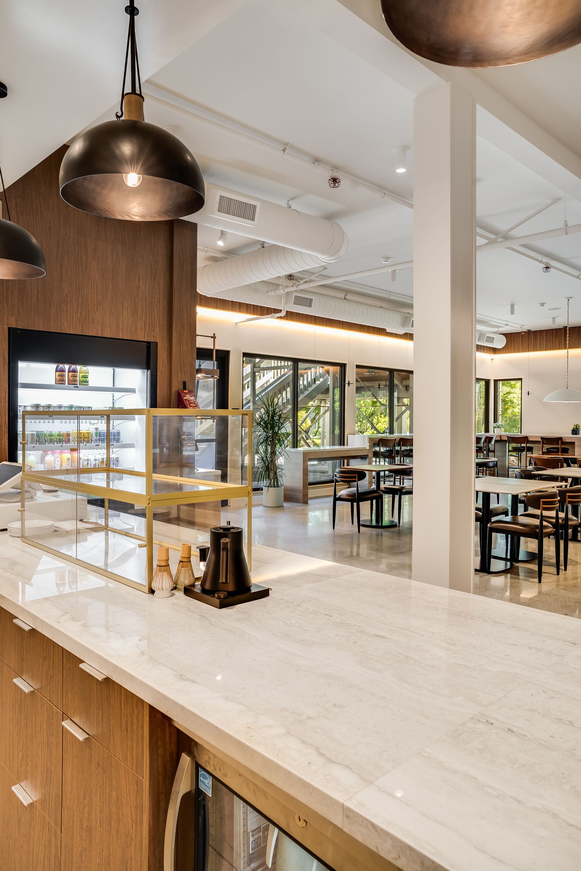 Modern café interior with wood counter, hanging lights, and seating area by large windows