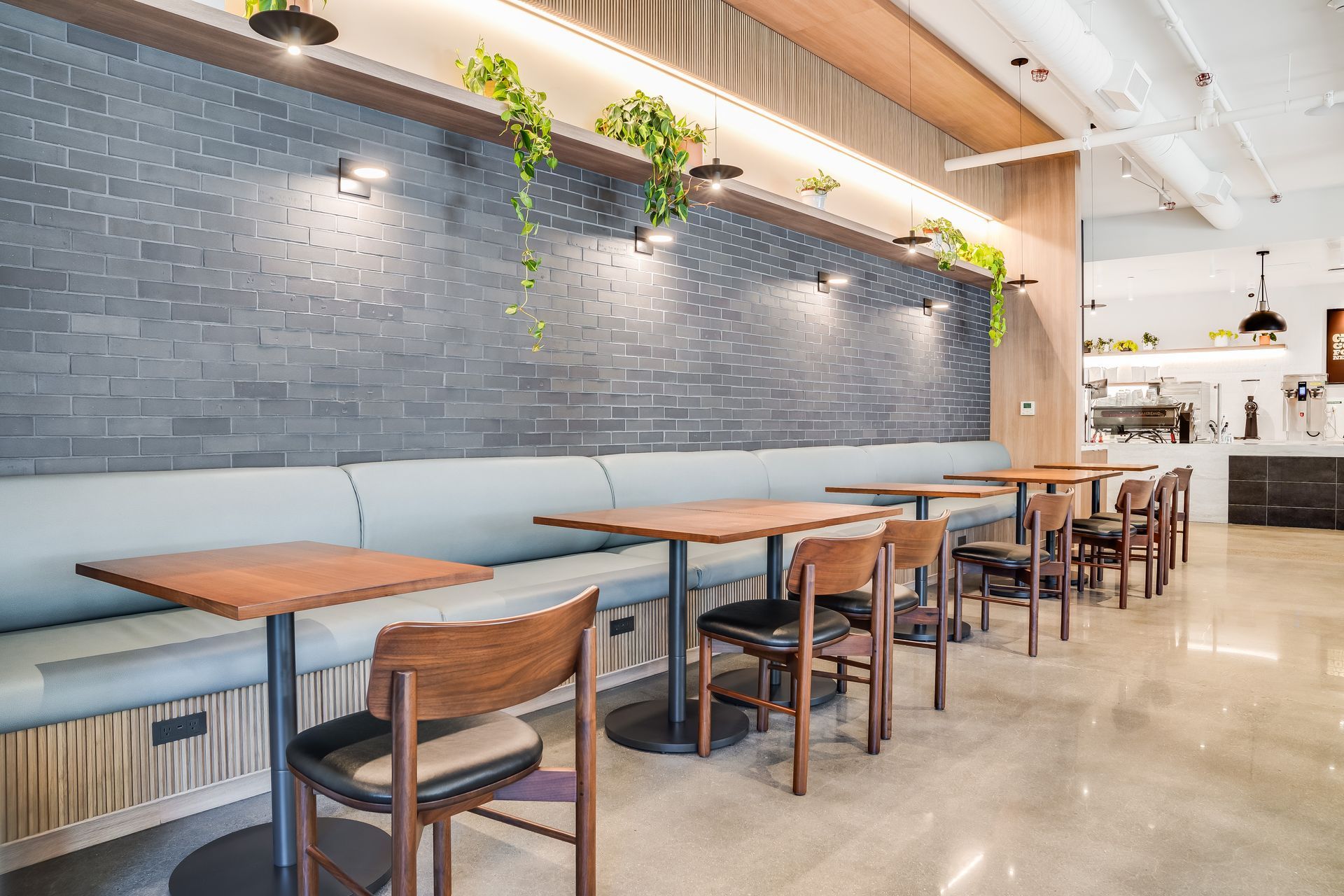 Modern cafe interior with blue tiled wall, hanging plants, and wooden tables and chairs