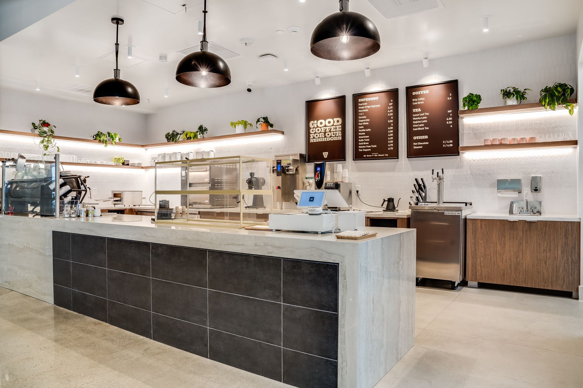 Modern café interior with a marble counter, black pendant lights, menu boards, and seating area