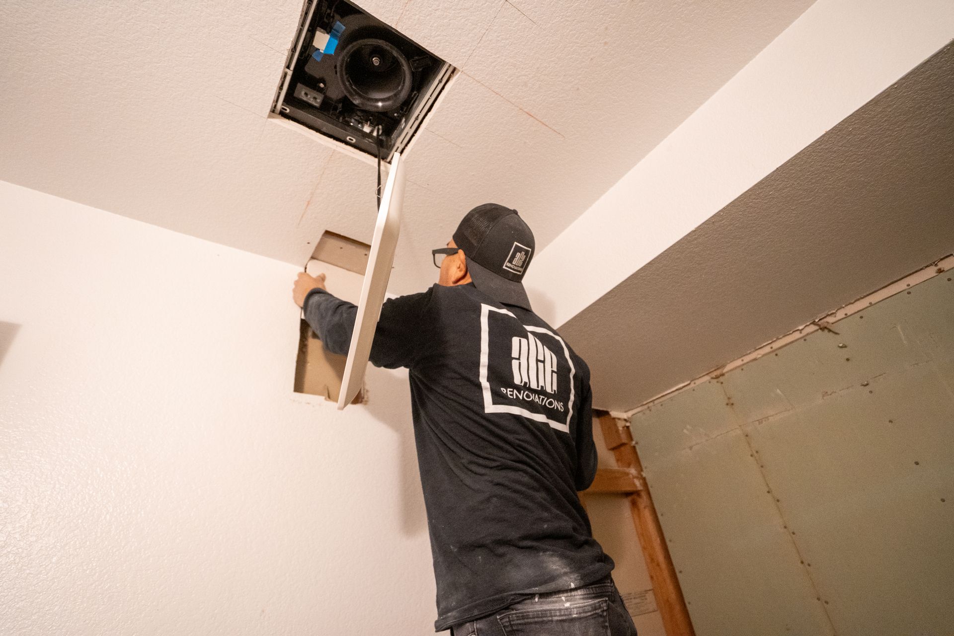 Person installing a ceiling vent with a long pole in a room with unfinished walls.