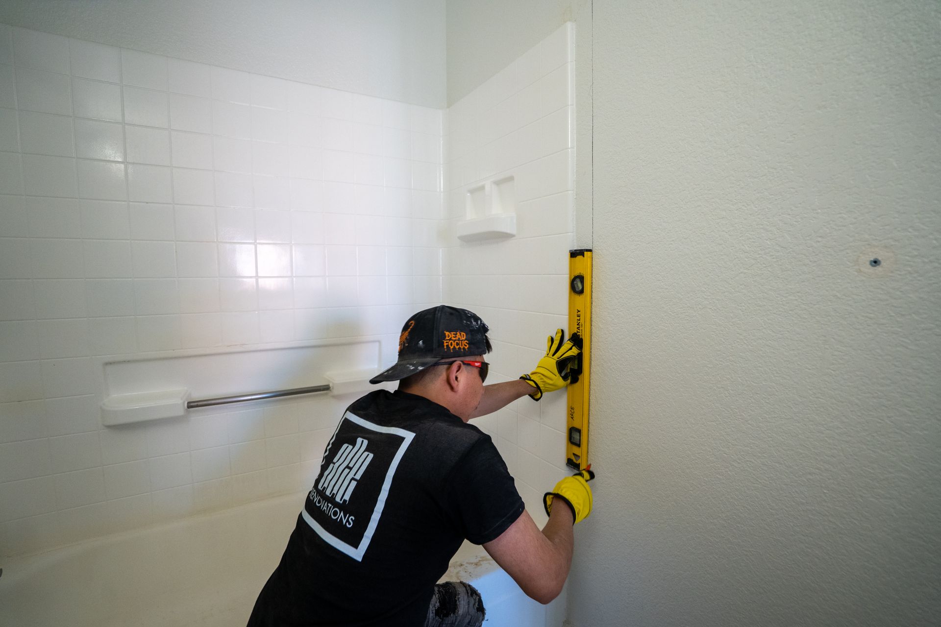 Person using a level to install a towel bar in a white tiled bathroom